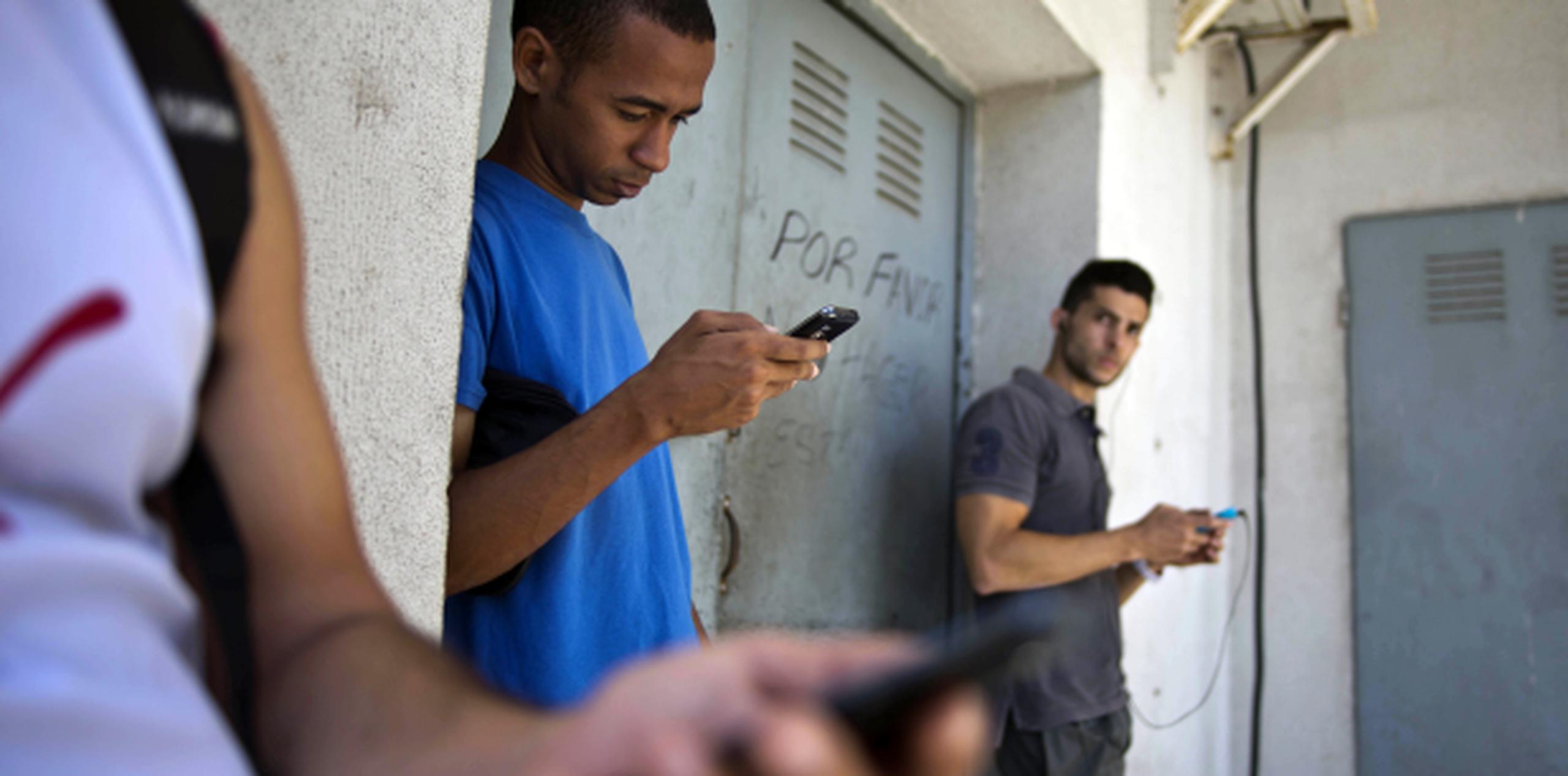 Estudiantes cubanos buscan señal cerca de un negocio en Cuba. (AP)