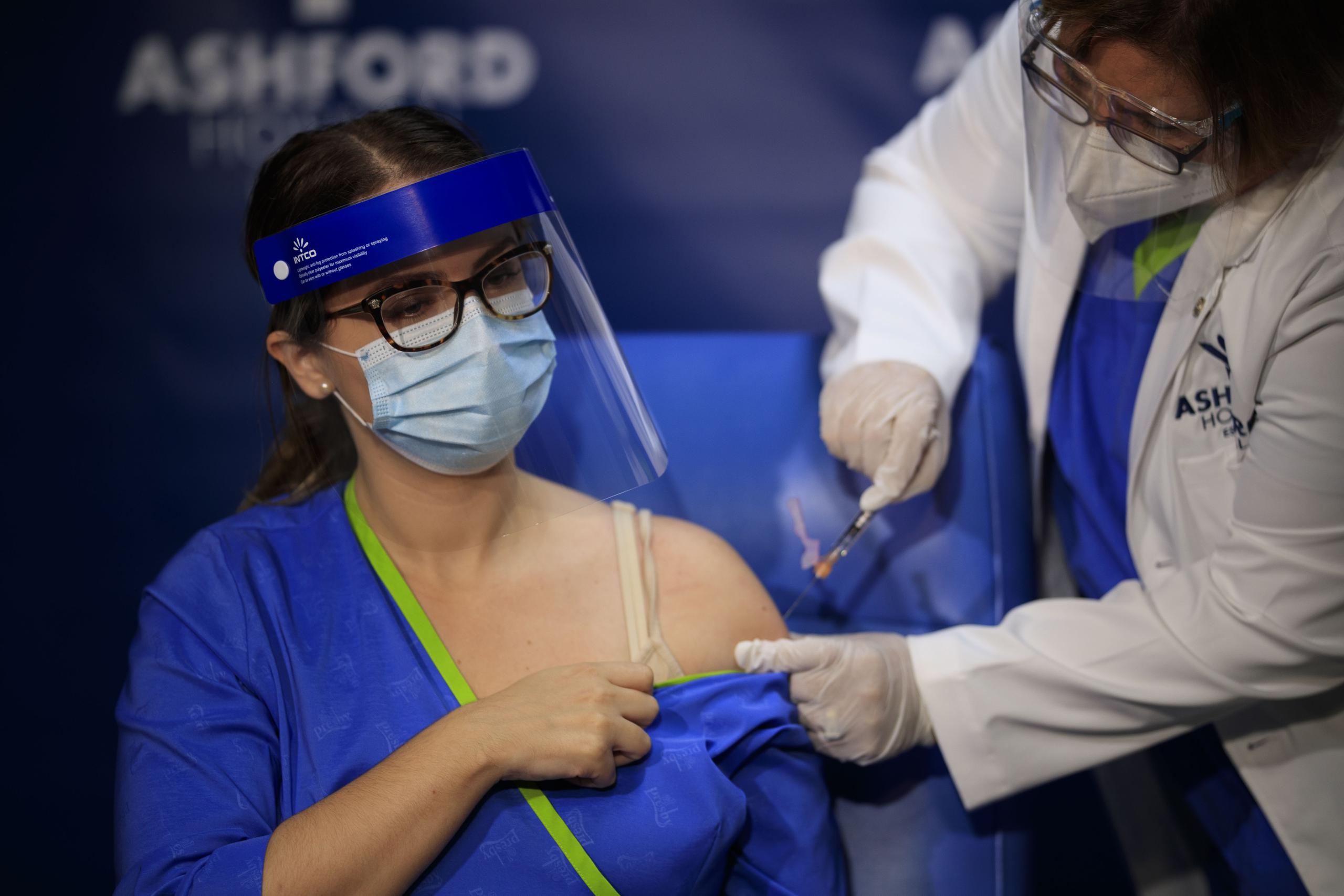 La epidemióloga Hilda Alemán administra una de las primeras vacunas contra el COVID-19 a Melisa Valentín, enfermera de salud ocupacional.