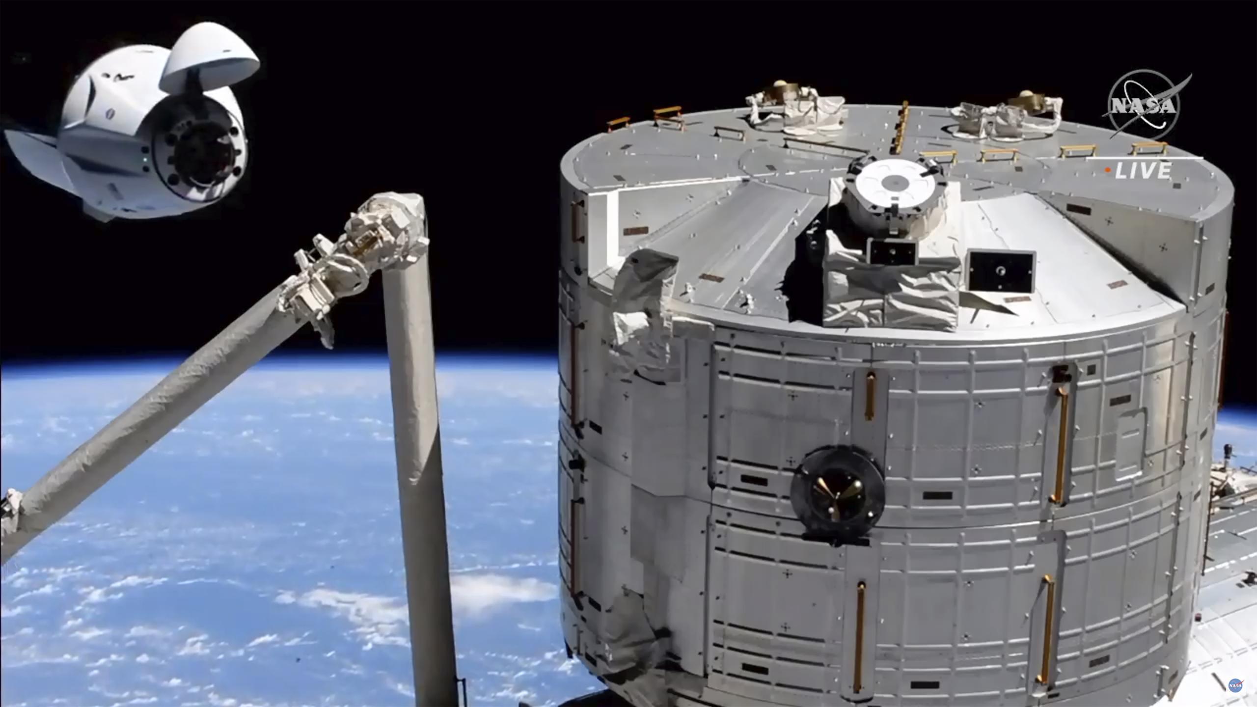 Momento en que la cápsula Crew Dragon de SpaceX (izquierda) se acerca a la Estación Espacial Internacional para el acoplamiento del sábado.