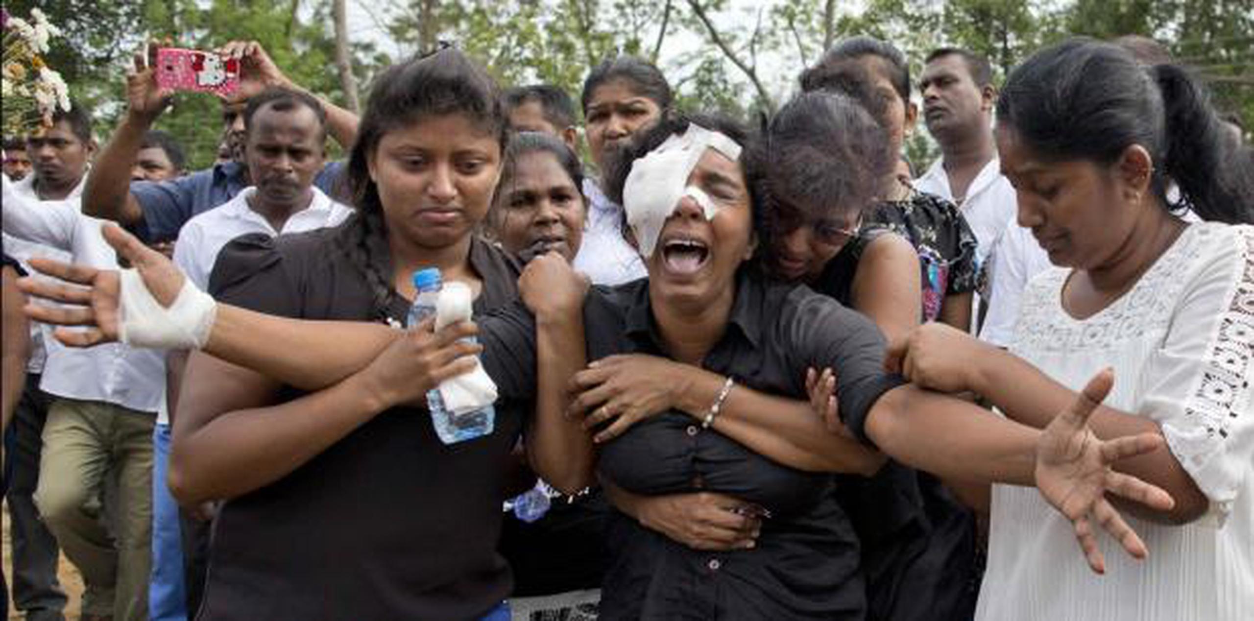 Anusha Kumari, con vendas en el ojo izquierdo, llora durante un entierro masivo para su esposo, dos hijos y tres hermanos, todos víctimas de los ataques terroristas. (AP / Gemunu Amarasinghe