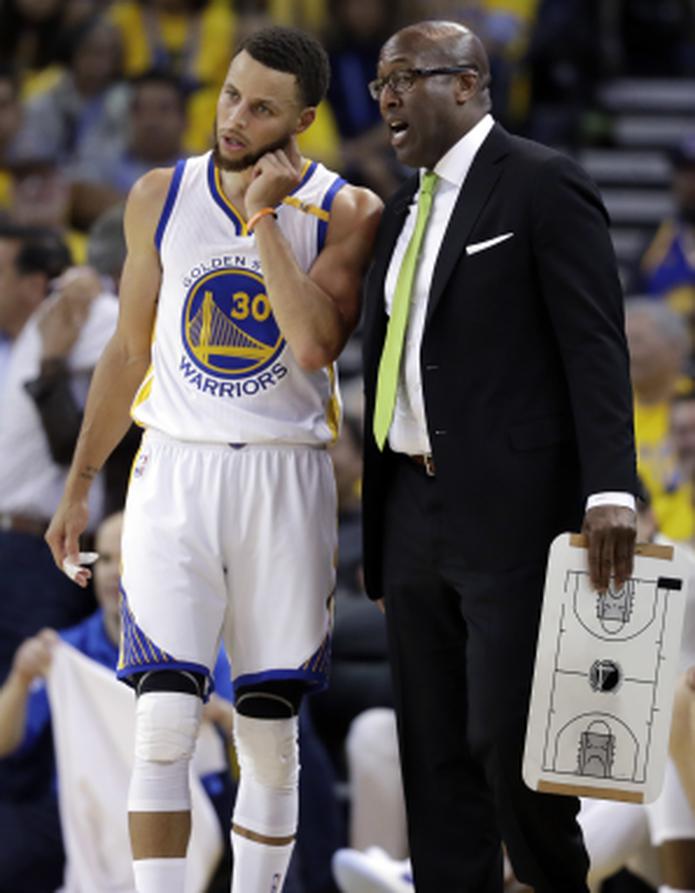 Mike Brown, con la tabla de instrucciones en mano y conversando con Stephen Curry, está nuevamente dirigiendo en la NBA ante un problema de salud del técnico Steve Kerr. (AP / Marcio Jose Sanchez)