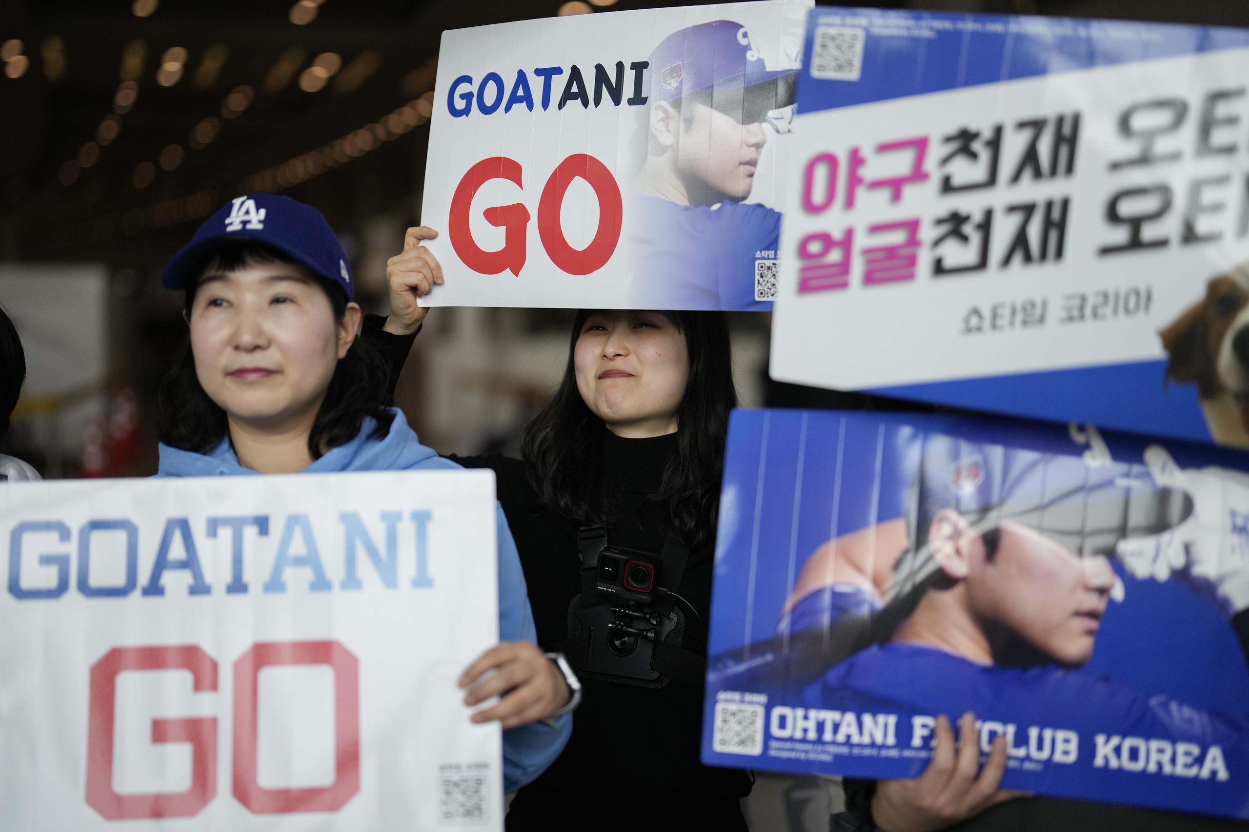 Seguidores del pelotero Shohei Ohtani de los Dodgers de Los Ángeles sostienen pancartas a la espera de verlo durante la gira de los Dodgers a Corea del Sur.