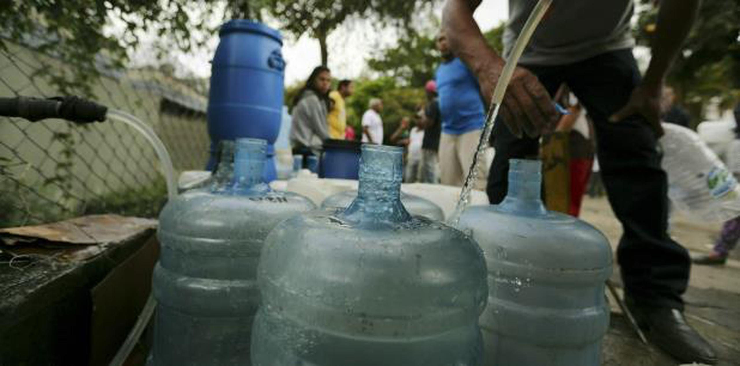 Varias personas almacenan agua. (AP)