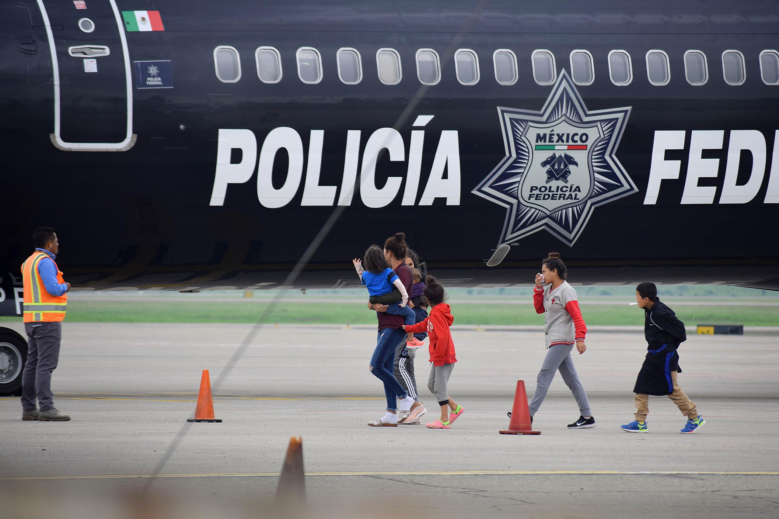 Un grupo de migrantes hondureños que hacía parte de la caravana rumbo a EE.UU. llega en un avión de la policía mexicana este miércoles al aeropuerto Ramón Villeda Morales, cerca de San Pedro Sula (Honduras), luego de ser deportados desde ese país.
