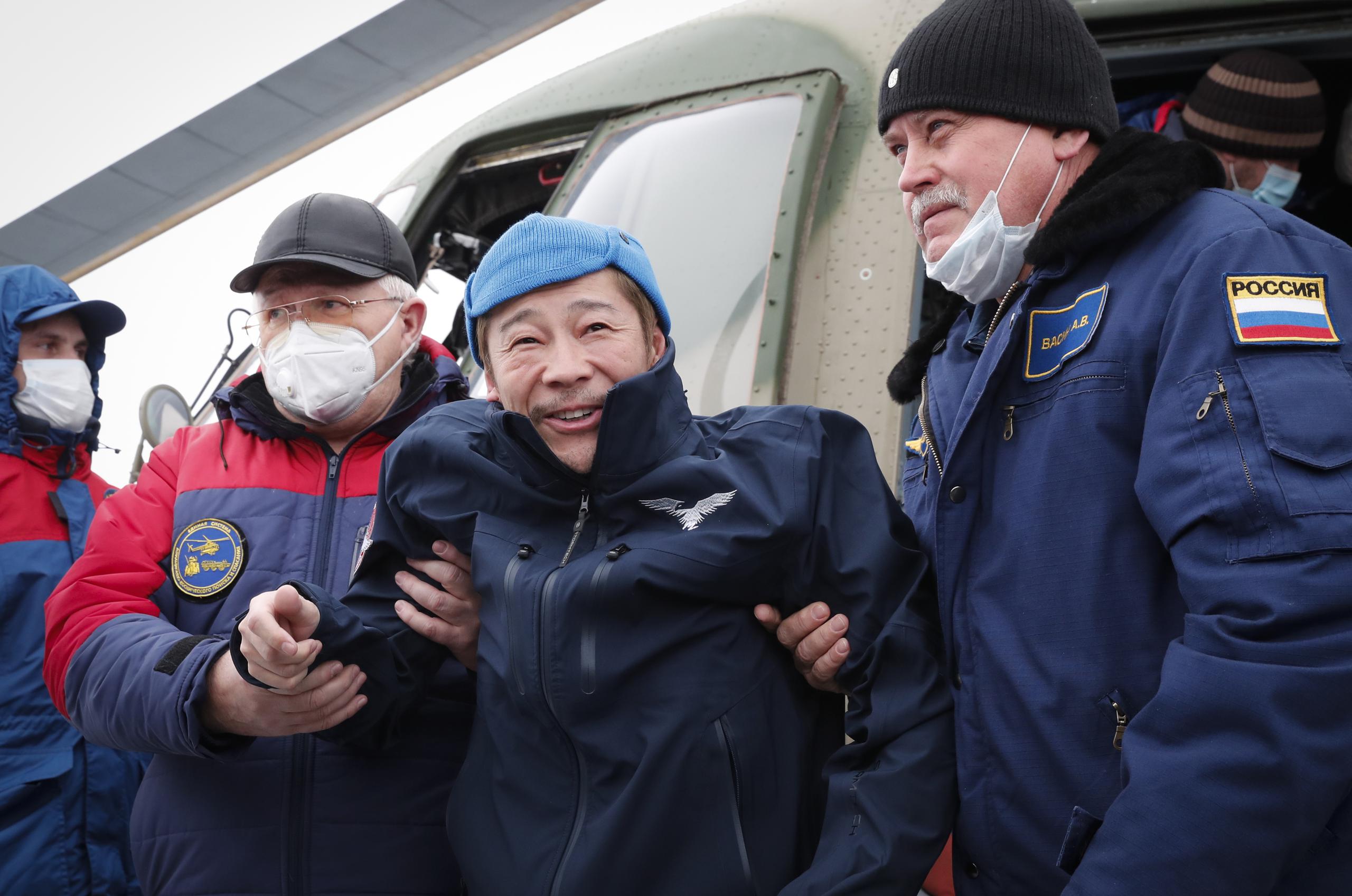 El turista espacial, el empresario japonés Yusaku Maezawa, es ayudado mientras baja de un helicóptero en Zhezkazgan, Kazajistán, el lunes 20 de diciembre de 2021. (Shamil Zhumatov/Pool Photo via AP)