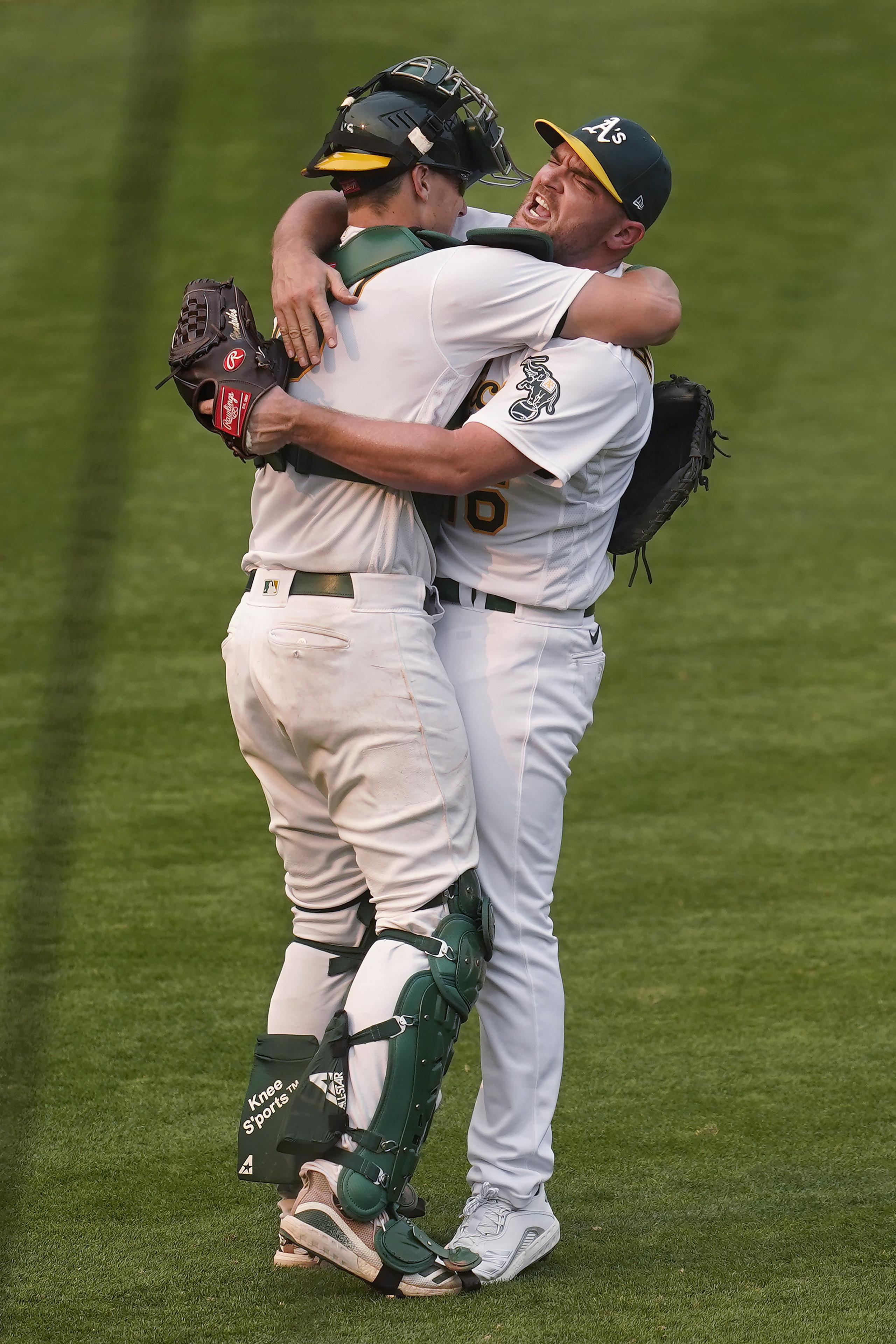 El receptor Sean Murphy y el lanzador Liam Hendriks, ambos de Oakland, se abrazan para festejar tras el último out del encuentro del jueves ante los White Sox.
