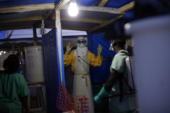 Un trabajador de salud es desinfectado luego de salir de la zona contaminada en el centro de atención de ébola en Gueckedou, Guinea.