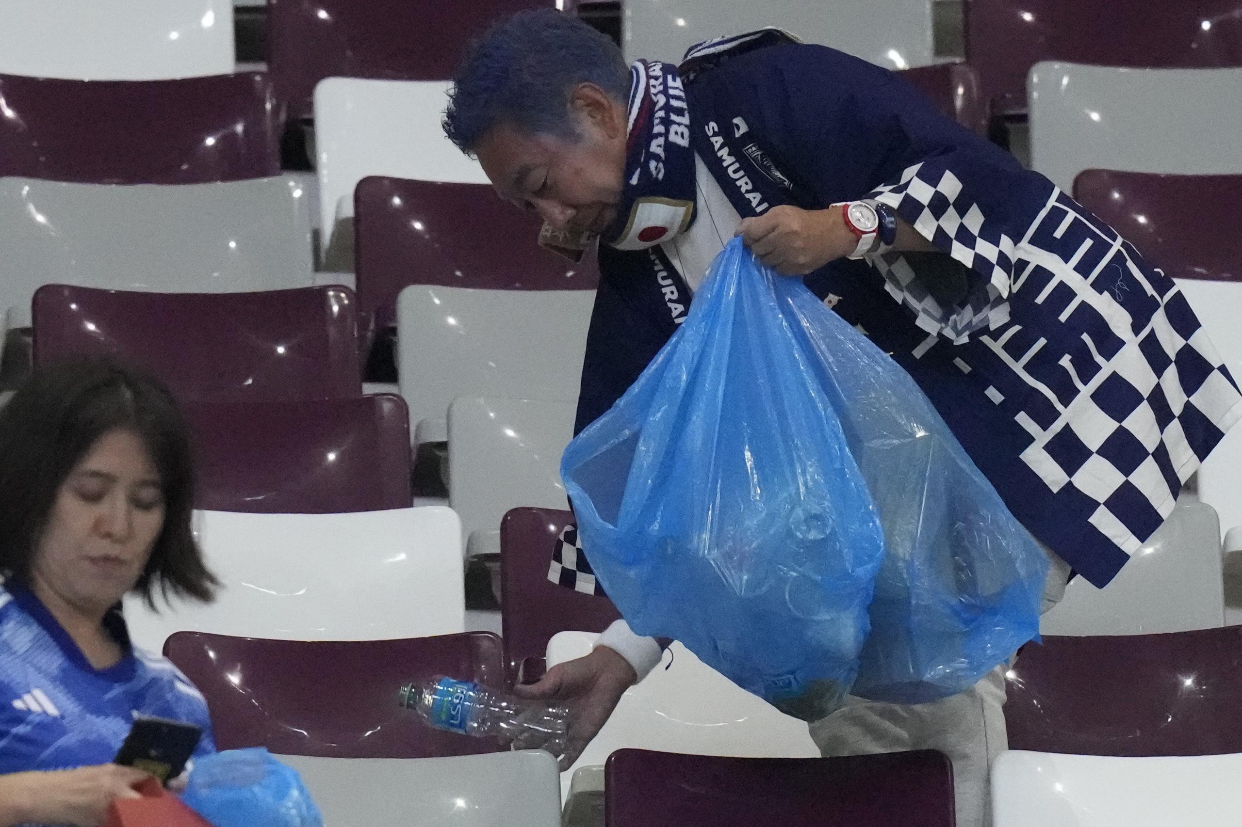 Fanáticos de Japón limpian las gradas al final del juego entre Alemania y Japón en el estadio Jalifa Internacional de Doha.