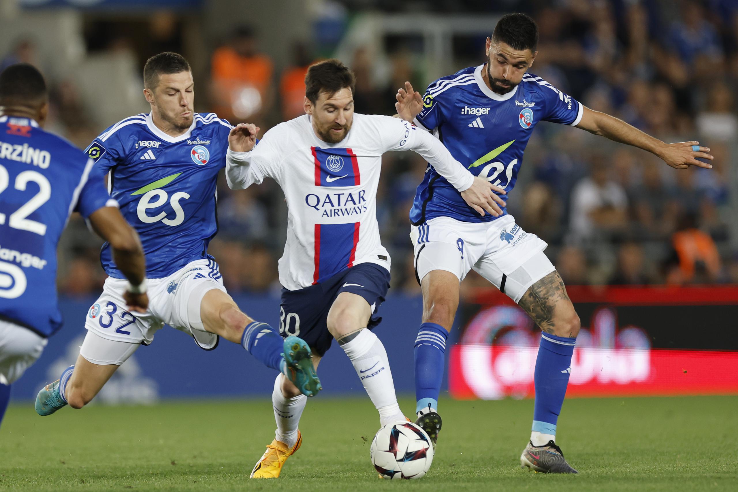 Lionel Messi (centro) del Paris Saint-Germain pugna el balón con Frederic Guilbert (izquierda) y Kevin Gameiro (derecha) de Estrasburgo en el empate 1-1 en el partido de la liga francesa, el sábado 27 de mayo de 2023.