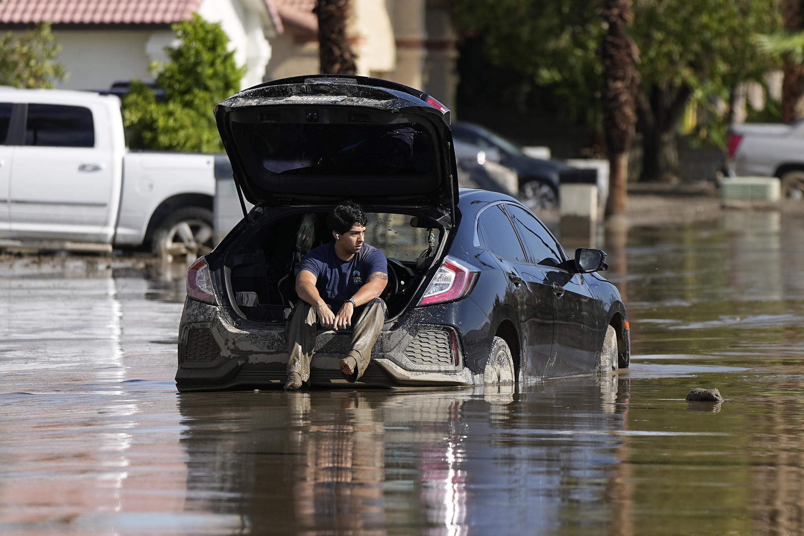 Dorian Padilla permanece en su automóvil mientras aguarda la llegada de una grúa después de que quedó atascado en el lodo, el lunes 21 de agosto de 2023, en Cathedral City, California. (AP Foto/Mark J. Terrill)