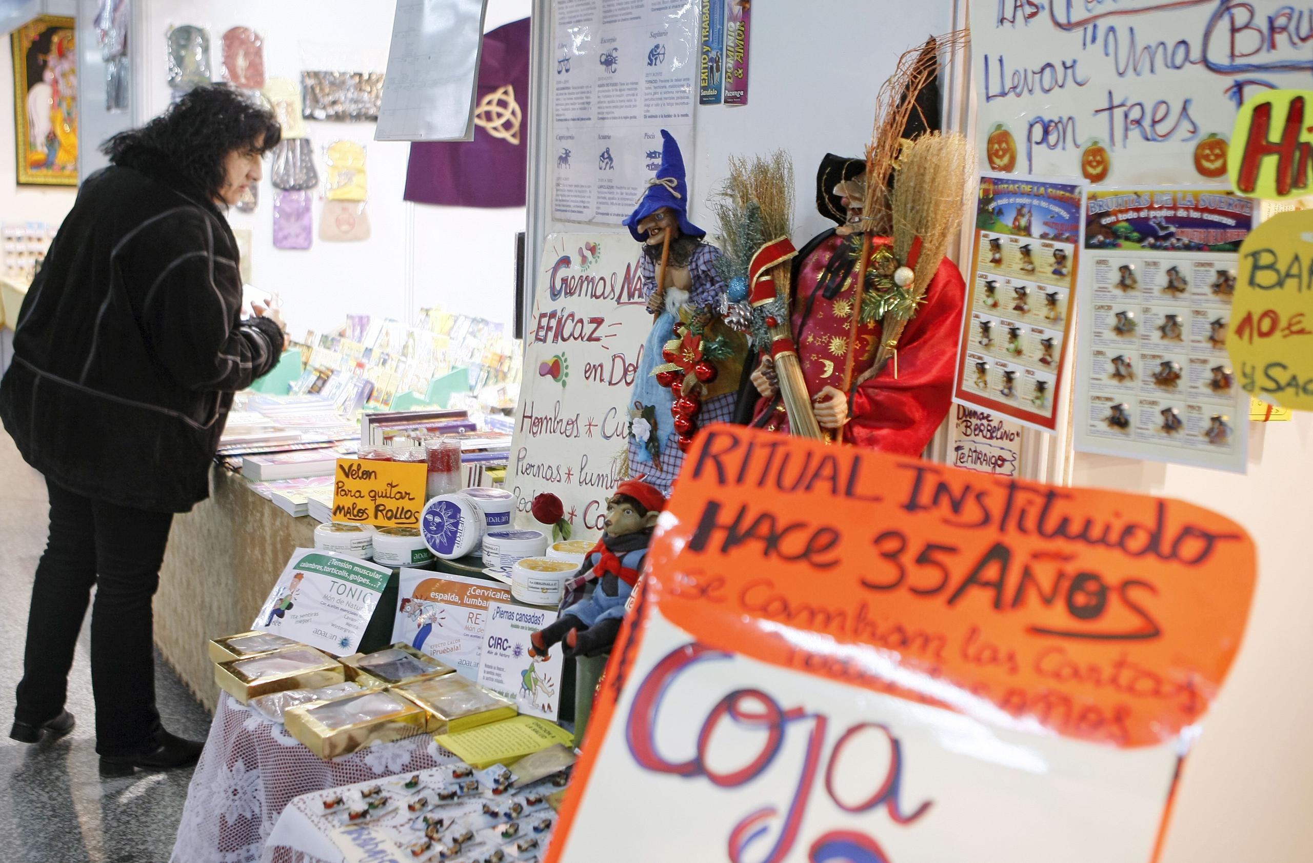 Una mujer observa unmostrador de objetos a la venta relacionados a ciencias ocultas y espirituales.