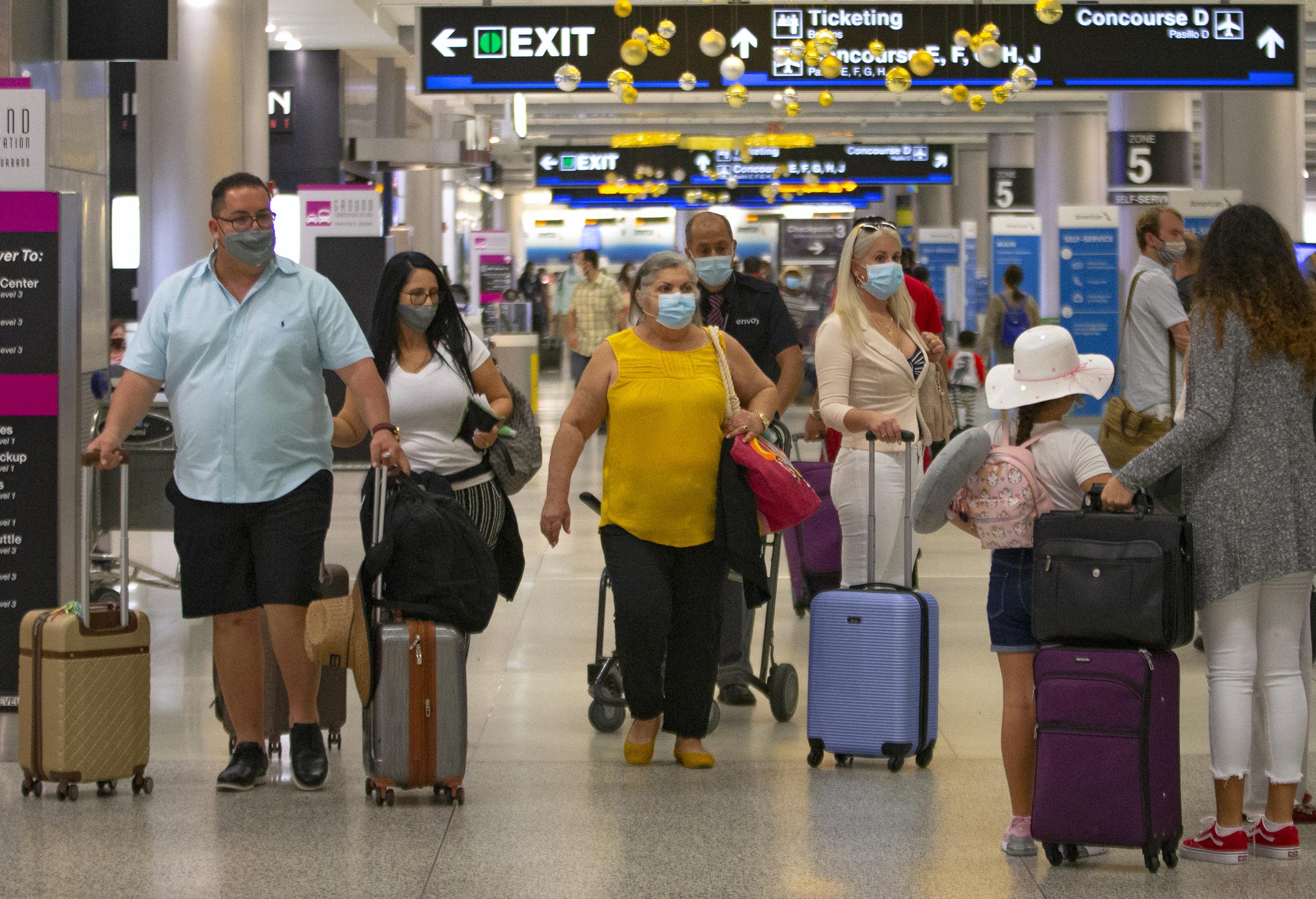 Viajeros con mascarillas para protegerse del coronavirus caminan por el Aeropuerto Internacional de Miami, en Florida.