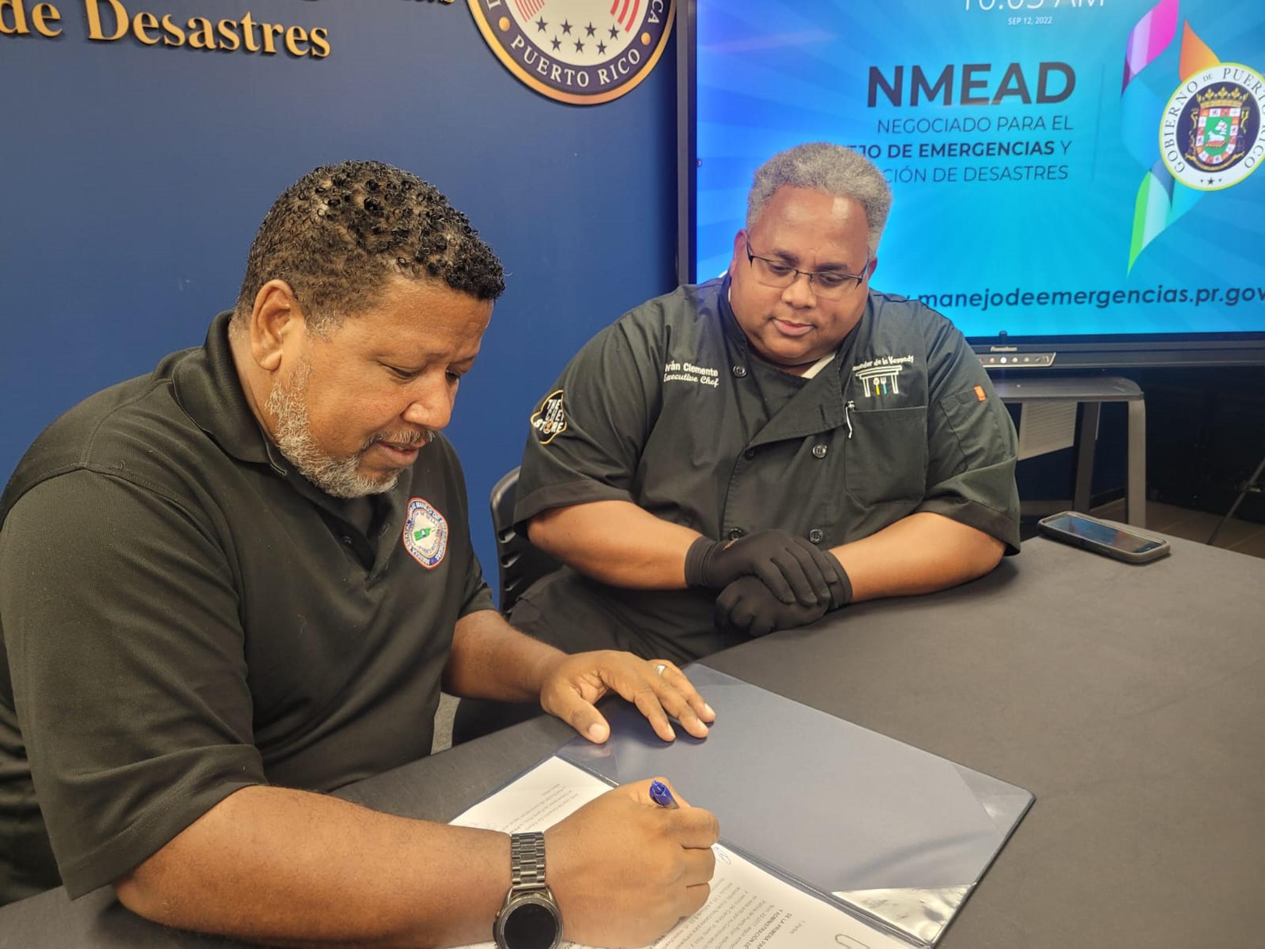 El comisionado del Negociado para el Manejo de Emergencias y Administración de Desastres (NMEAD), Nino Correa Filomeno, y el chef Iván Clemente del Comedor de la Kennedy, durante la firma del acuerdo el lunes, 12 de septiembre de 2022.