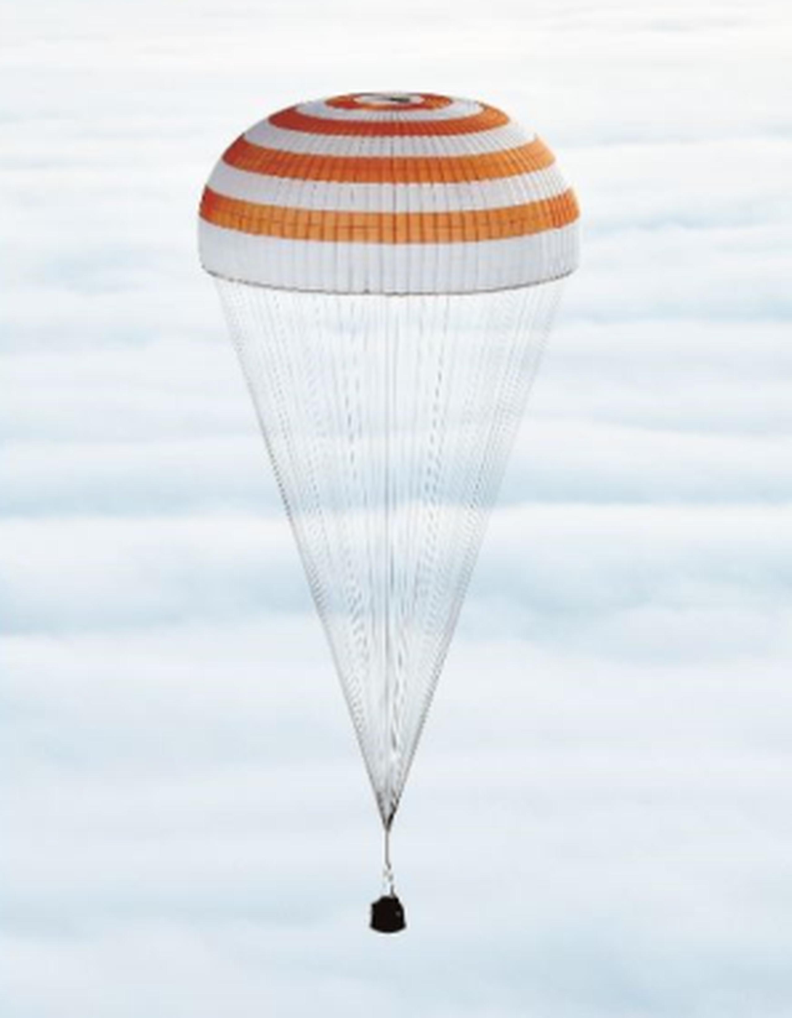 La capsula soyuz que trasladó a los astronautas descendió con un paracaídas rojo y blanco. (Archivo)