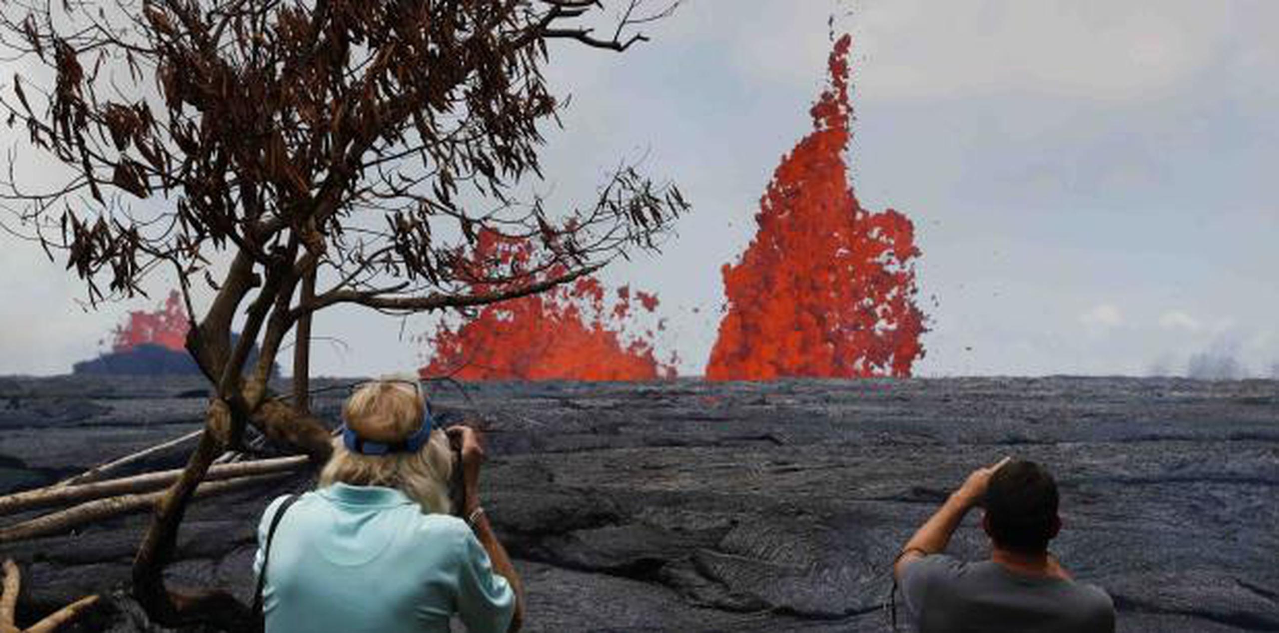 Dos personas toman fotos a lo lejos de erupciones del volcán. (AP)