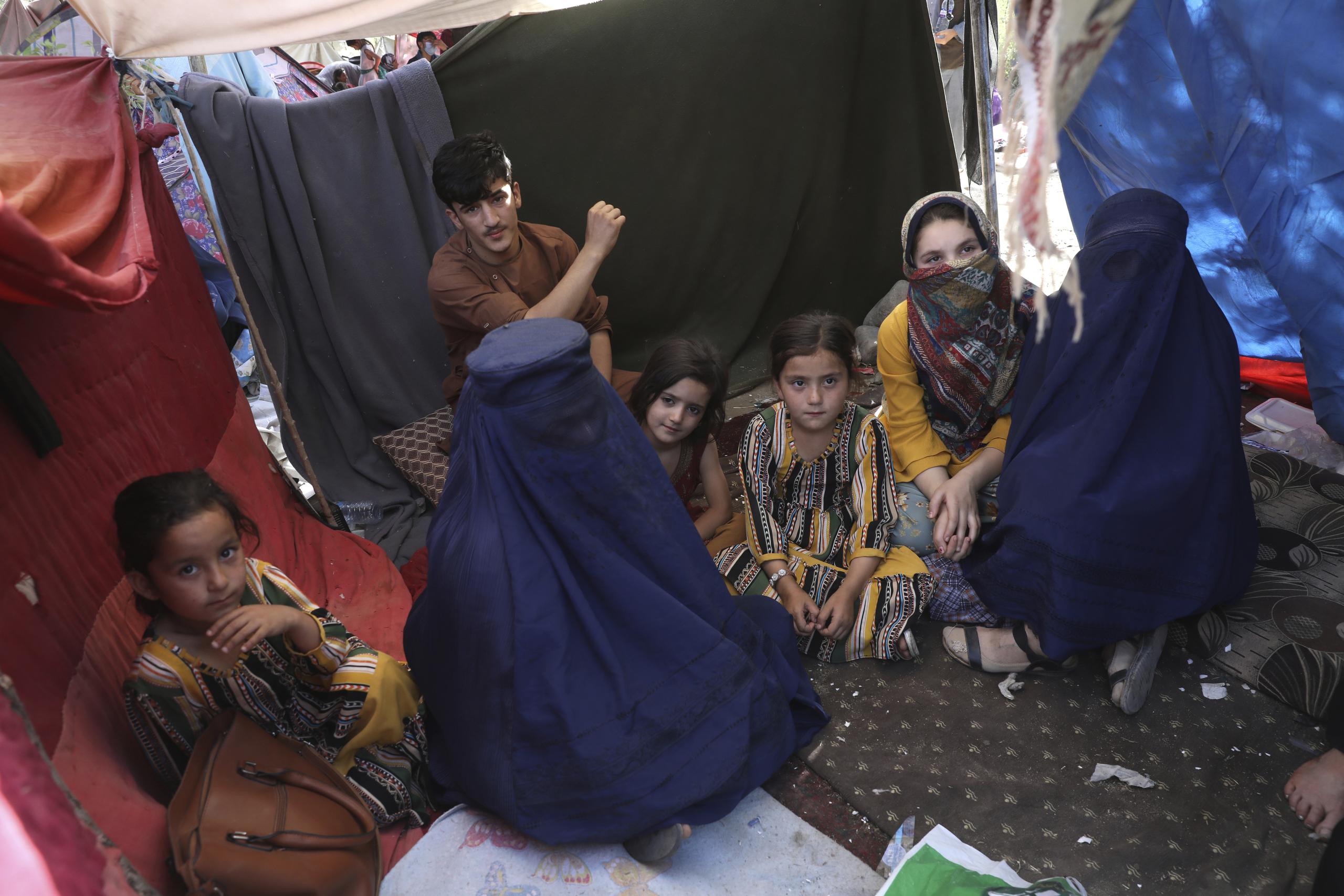 En esta foto del 13 de agosto de 2021, una profesora desplazada (izquierda), quien porta una burka y se identificó con su nombre Nilofar, habla con The Associated Press durante una entrevista en el interior de su tienda de campaña, en un parque público de Kabul, Afganistán.