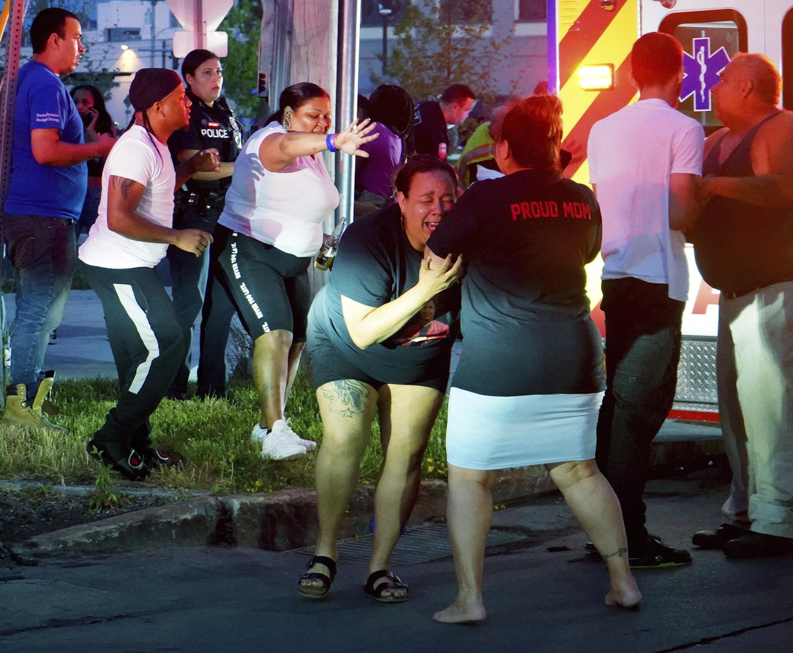 Una mujer llora mientras trabajadores de emergencias suben a personas heridas a las ambulancias después de una balacera en una fiesta en Syracuse, Nueva York