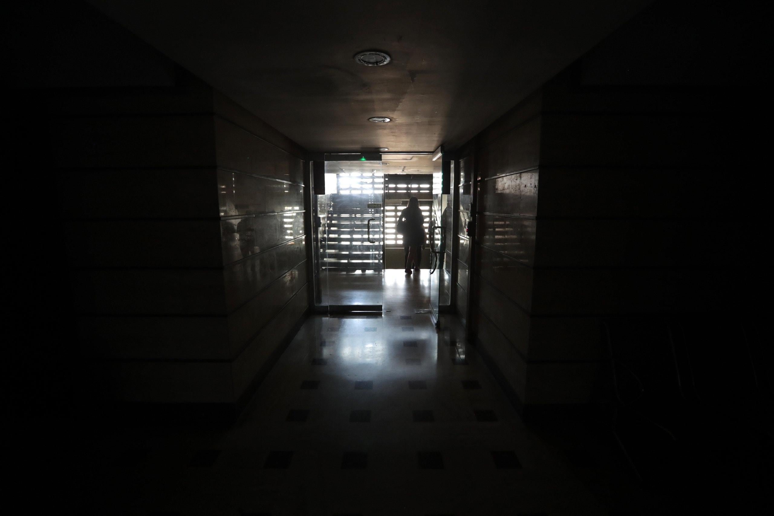 Una persona se ve al final de un pasillo en medio de la oscuridad al interior del edificio de la Asamblea Nacional este lunes en Caracas. (EFE)