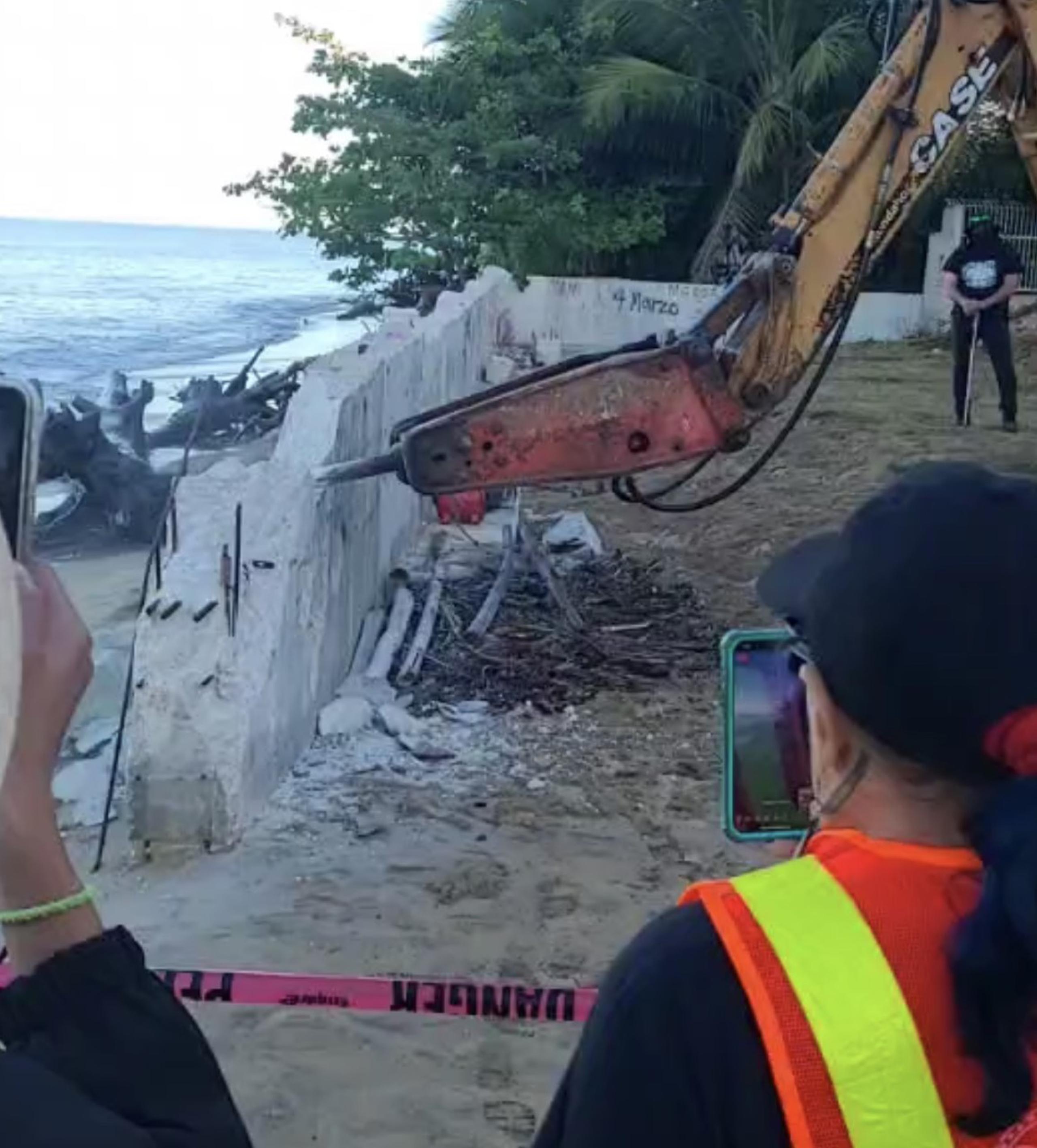 Un grupo de manifestantes comenzaron a demoler esta mañana los escombros del muro en la playa Los Almendros.