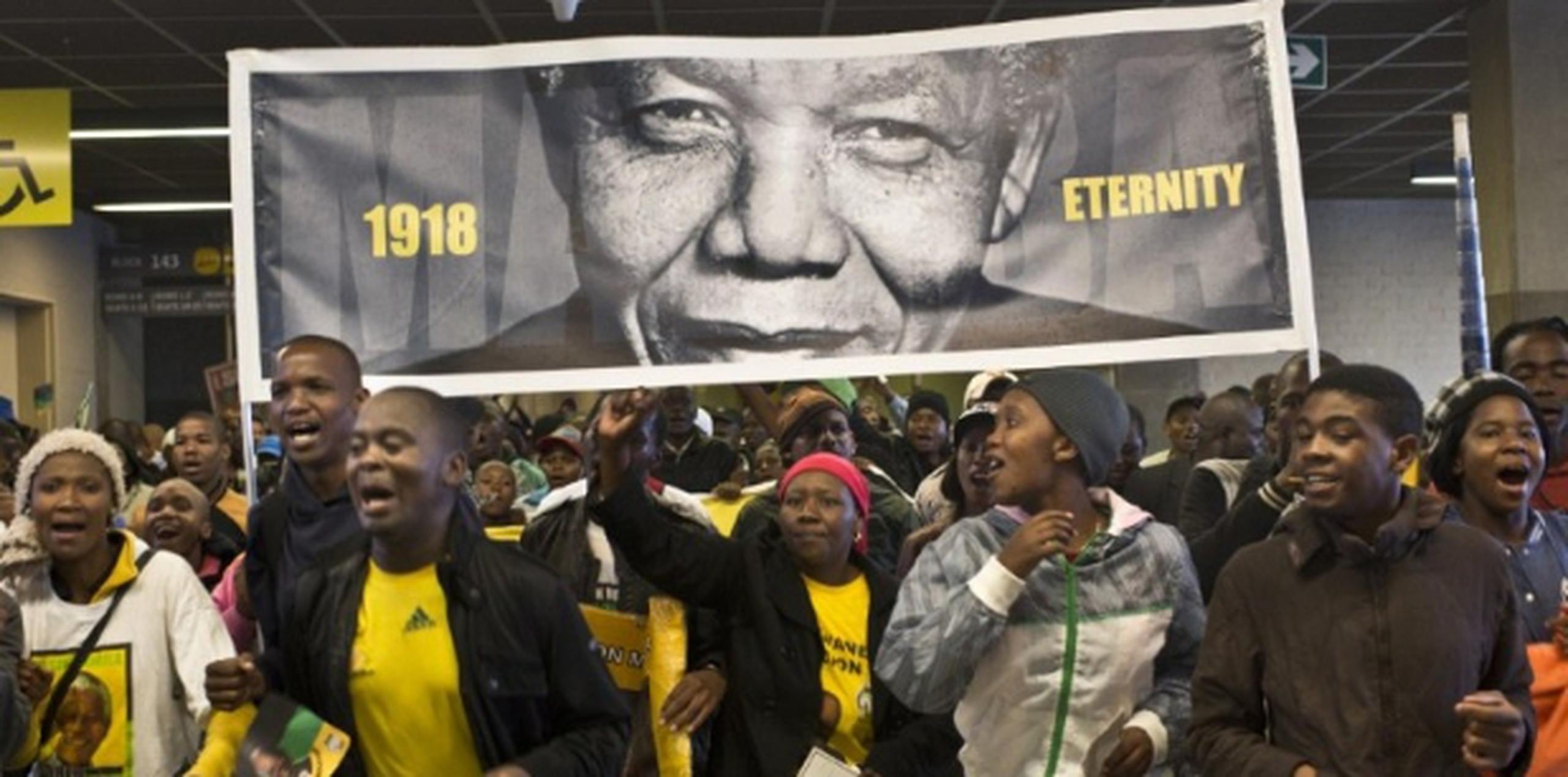 Un grupo de personas cargando un cartelón de  Mandela llegan al estadio Soccer City de Johannesburgo para el servicio fúnebre del ex presidente. El  Soccer City albergó la final de la Copa Mundial del 2010. (AFP / Pedro Ugarte)
