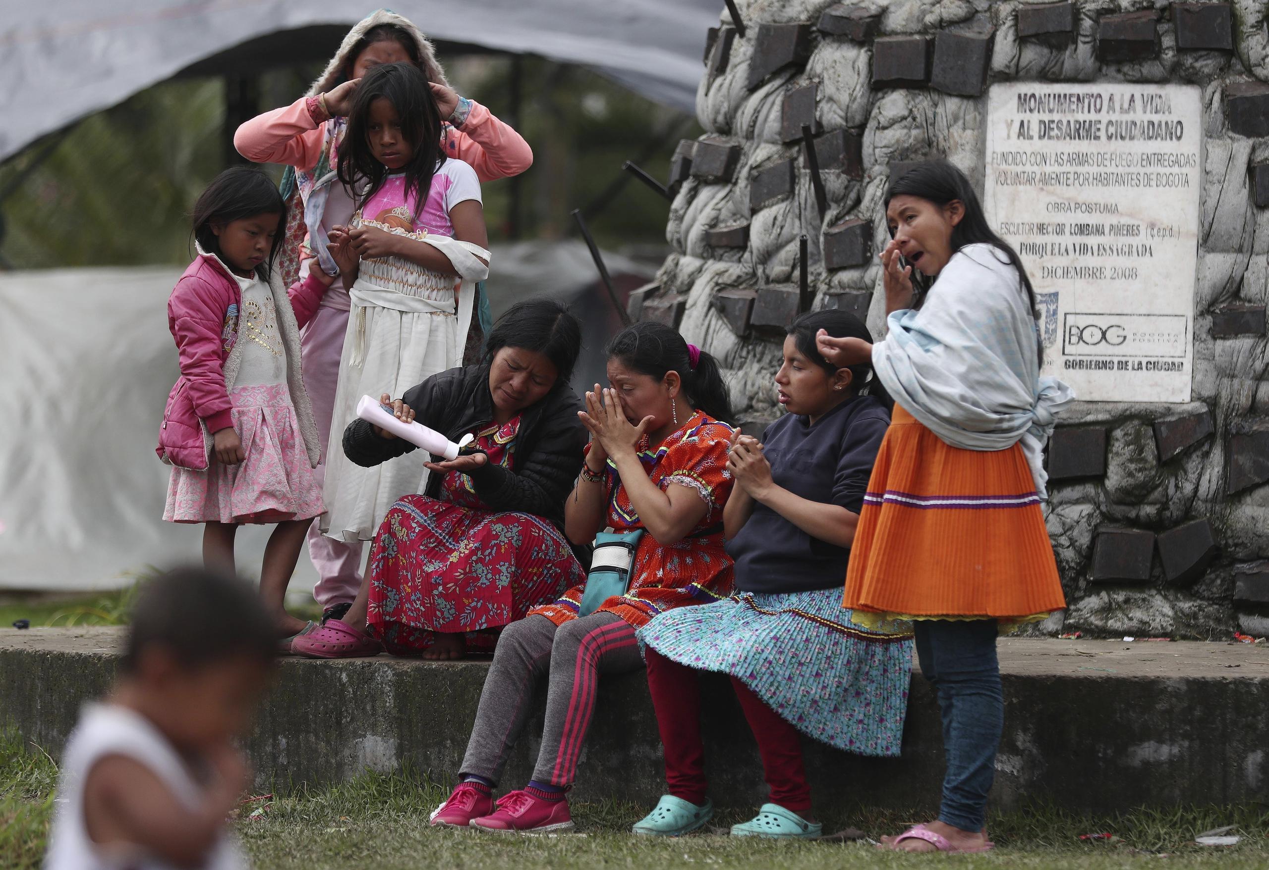 Miembros de la tribu Embera-Katio comparten una botella de crema corporal en un parque donde establecieron un refugio tras ser desalojados de sus horas por no pagar la renta debido a la pandemia del nuevo coronavirus en Bogotá, Colombia.
