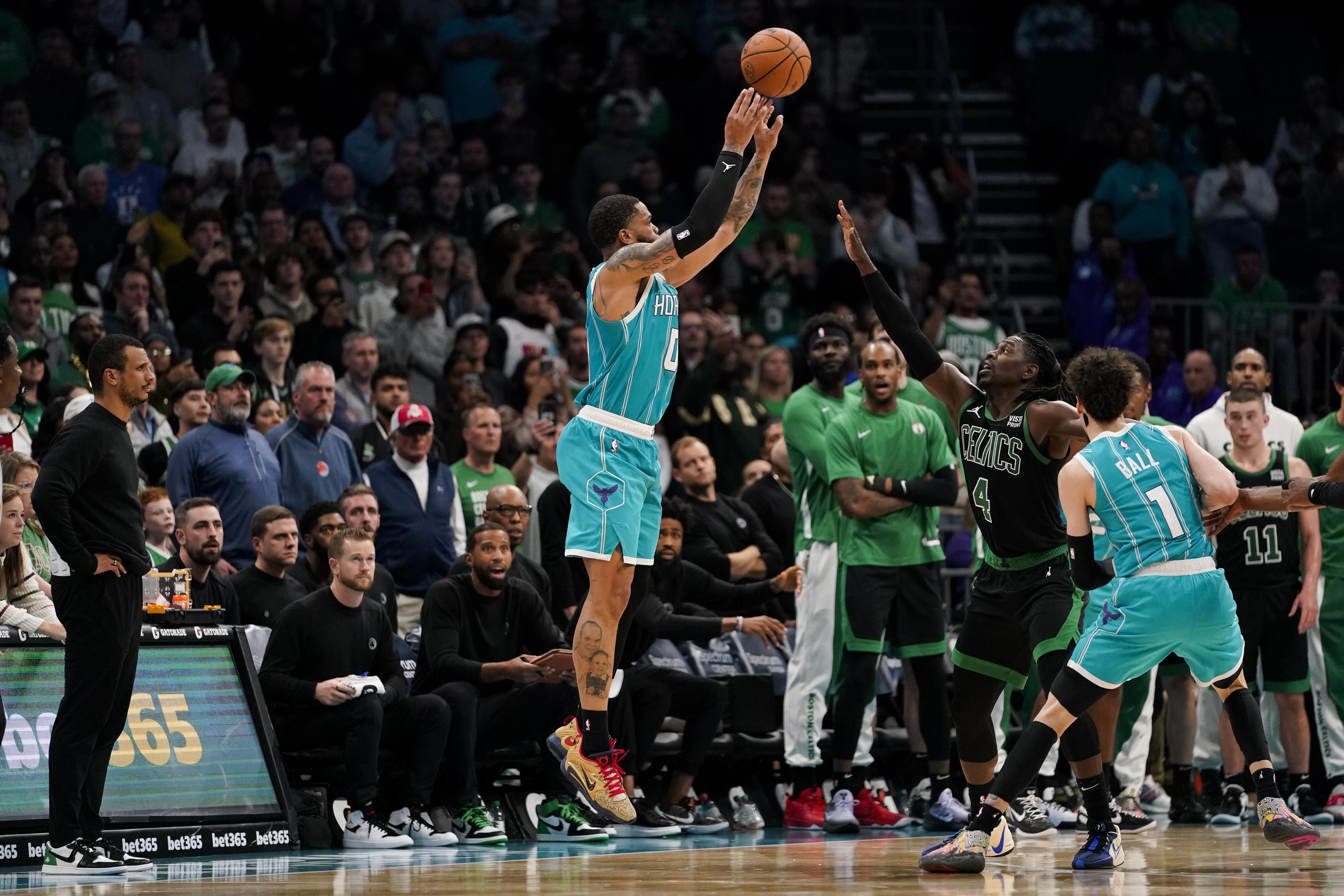 El alero de los Hornets de Charlotte Miles Bridges lanza el balón bajo presión del base de los Celtics de Boston Jrue Holiday en el tiempo extra del encuentro del lunes 20 de noviembre del 2023. (AP Foto/Erik Verduzco)