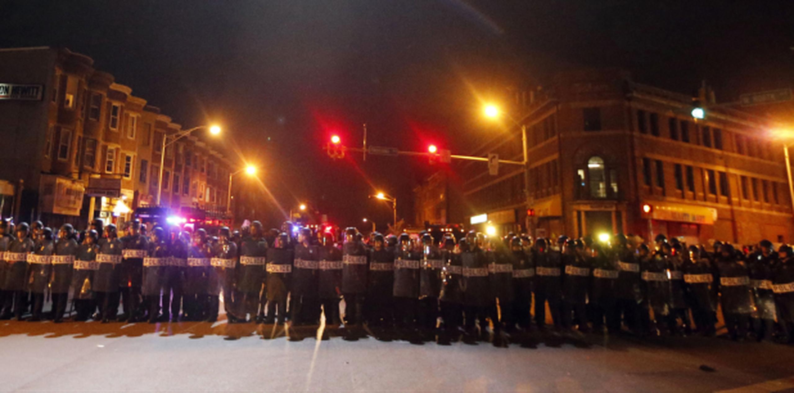Policías de Baltimore prestaban vigilancia anoche durante el toque de queda ordenado tras los disturbios en esa ciudad. (Prensa Asociada)