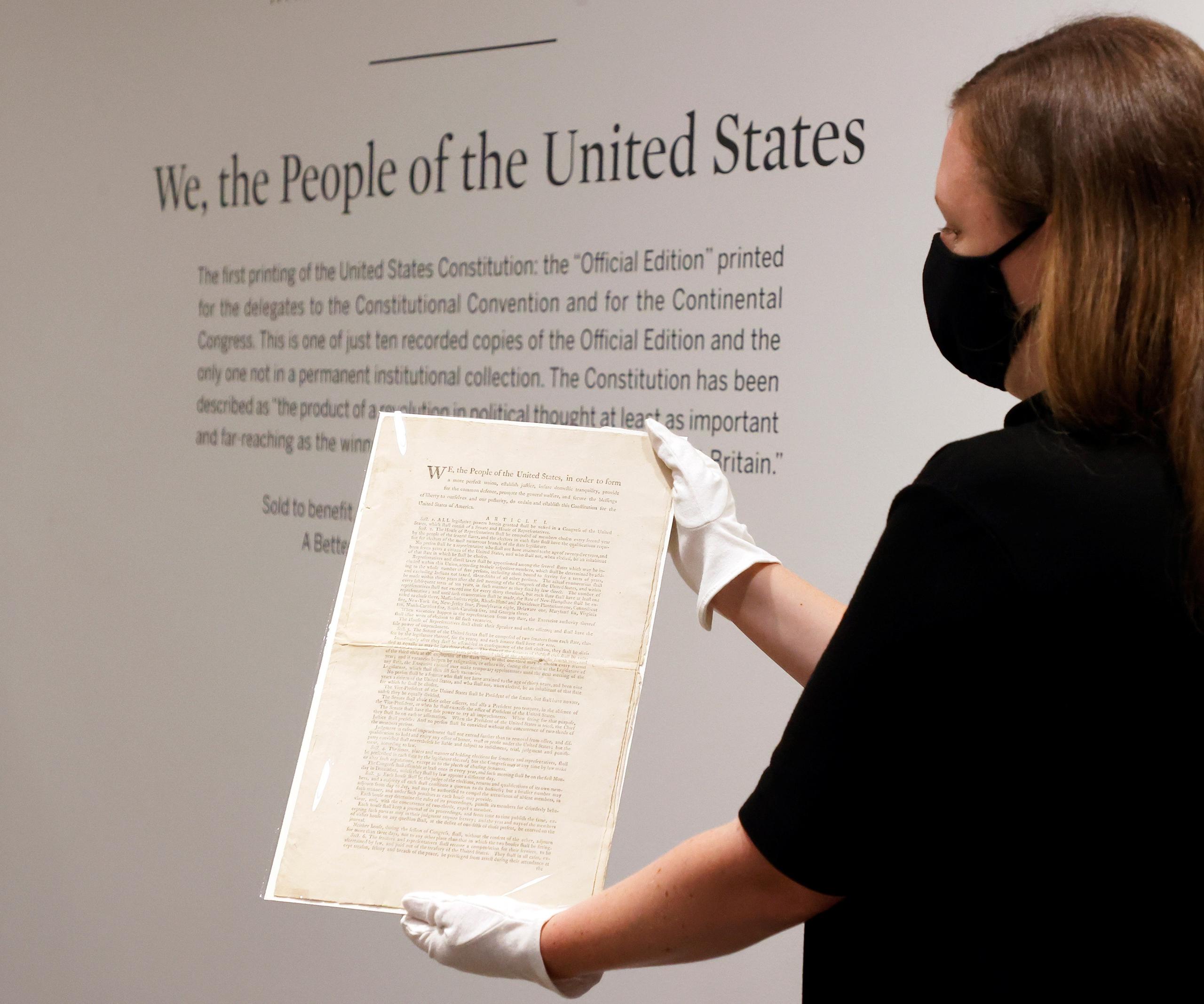 Una especialista en libros y manuscritos de Sotheby's sostiene una copia de la Constitución de los Estados Unidos de 1787.