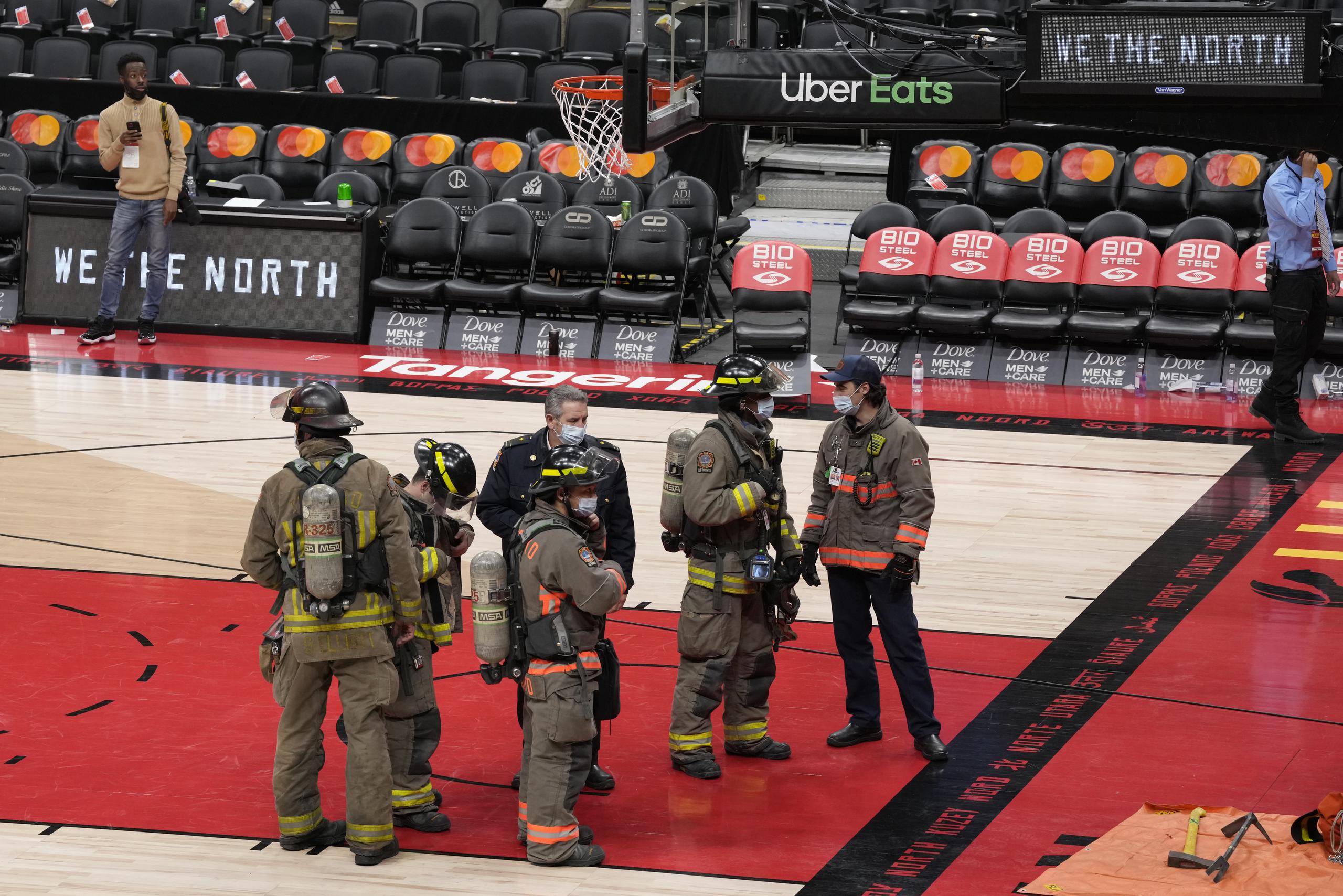 Bomberos y otros funcionarios observan desde el tabloncillo de la cancha de los Raptors de Toronto durante el incidente del sábado.