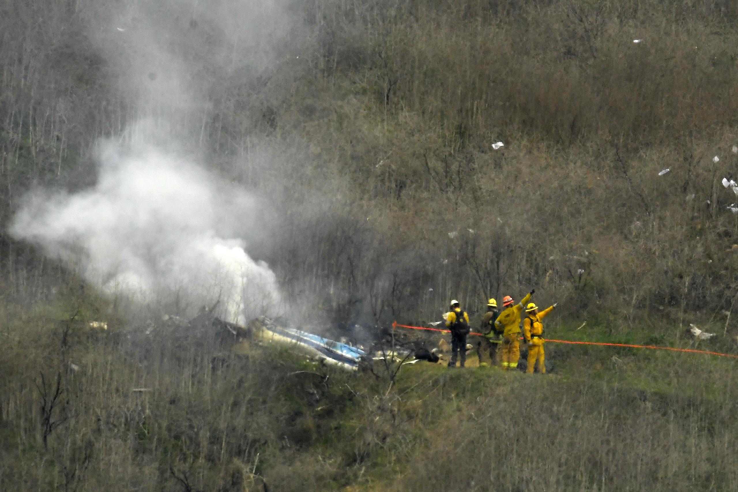 En esta foto del 26 de enero de 2020, los bomberos apagan restos del helicóptero que se estrelló en la localidad de Calabasas, California, causando la muerte de Kobe Bryant y de otras ocho personas.