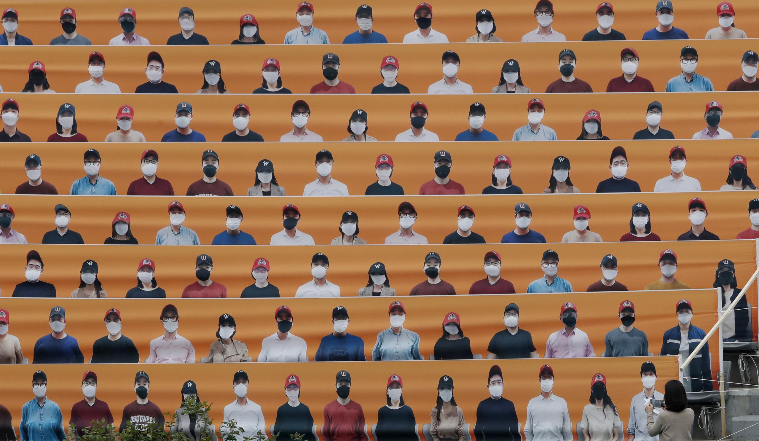 Una mujer toma una foto de las gradas del estadio, cubierta con fotos de aficionados, previo a un juego de la liga de béisbol de Corea del Sur en Incheon.