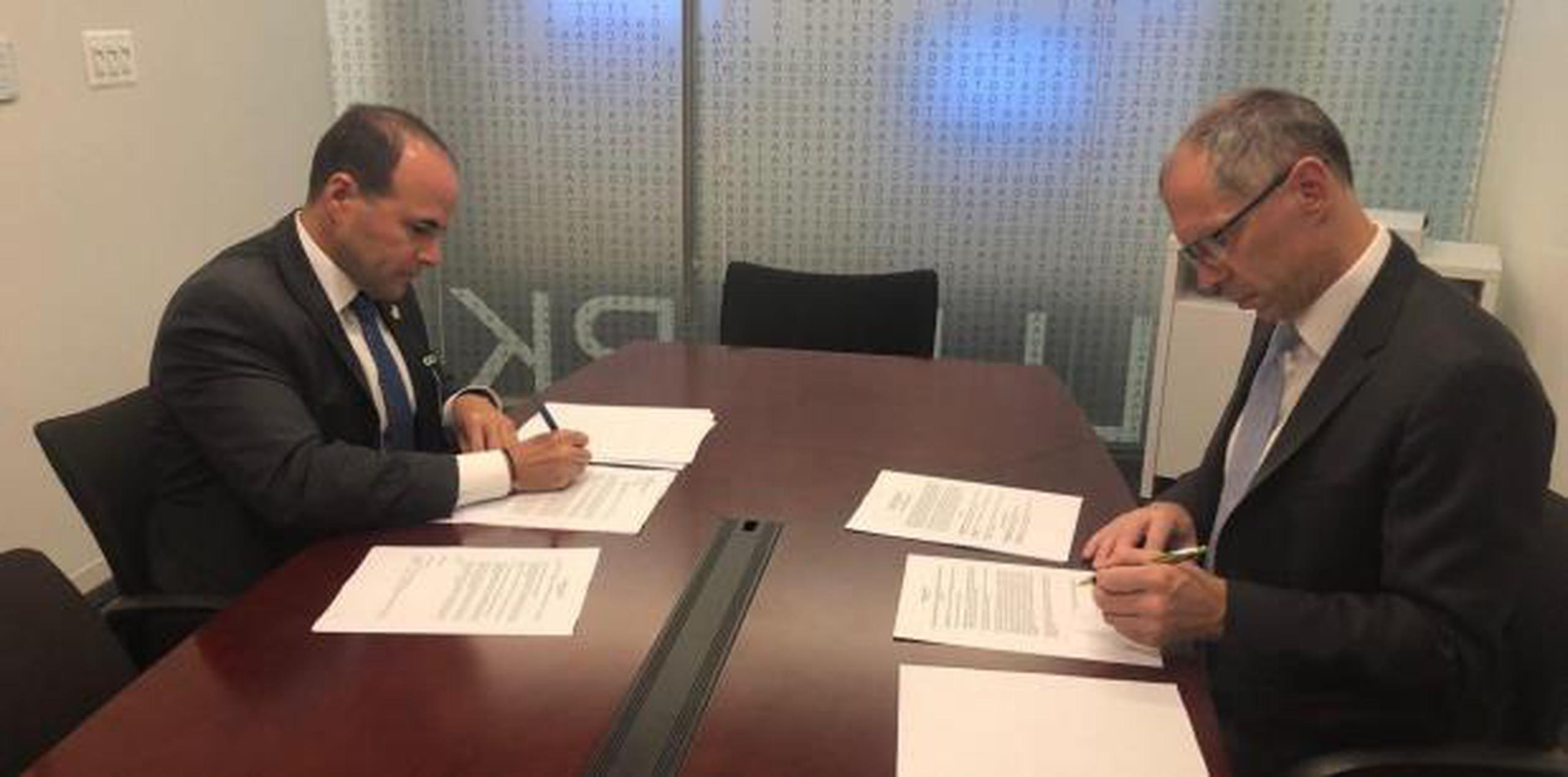 El secretario del DSP, Elmer L. Román González y Michael Cariola, CEO y presidente de Bode, firman el contrato para el análisis de los safe kits. (Suministrada)