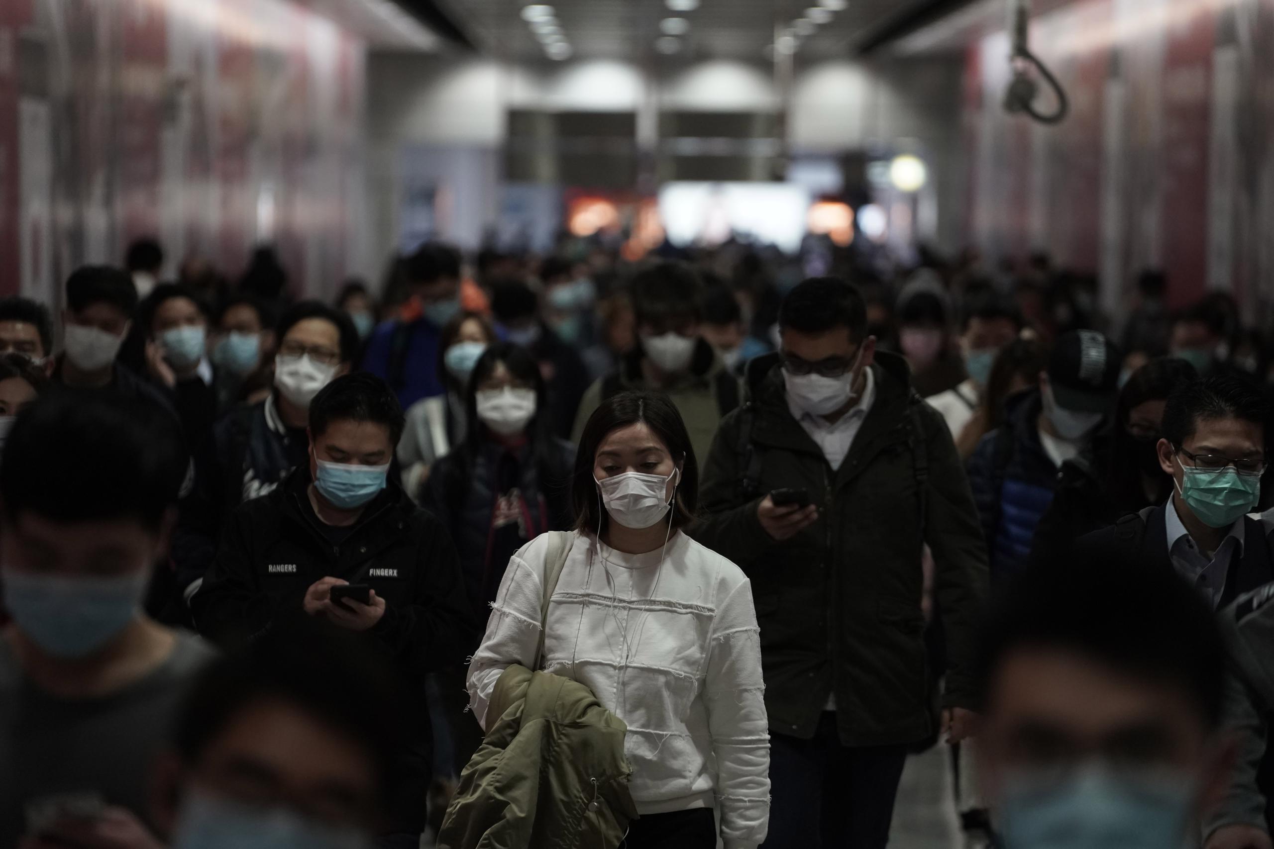 Personas con mascarillas caminan en una estación del tren subterráneo