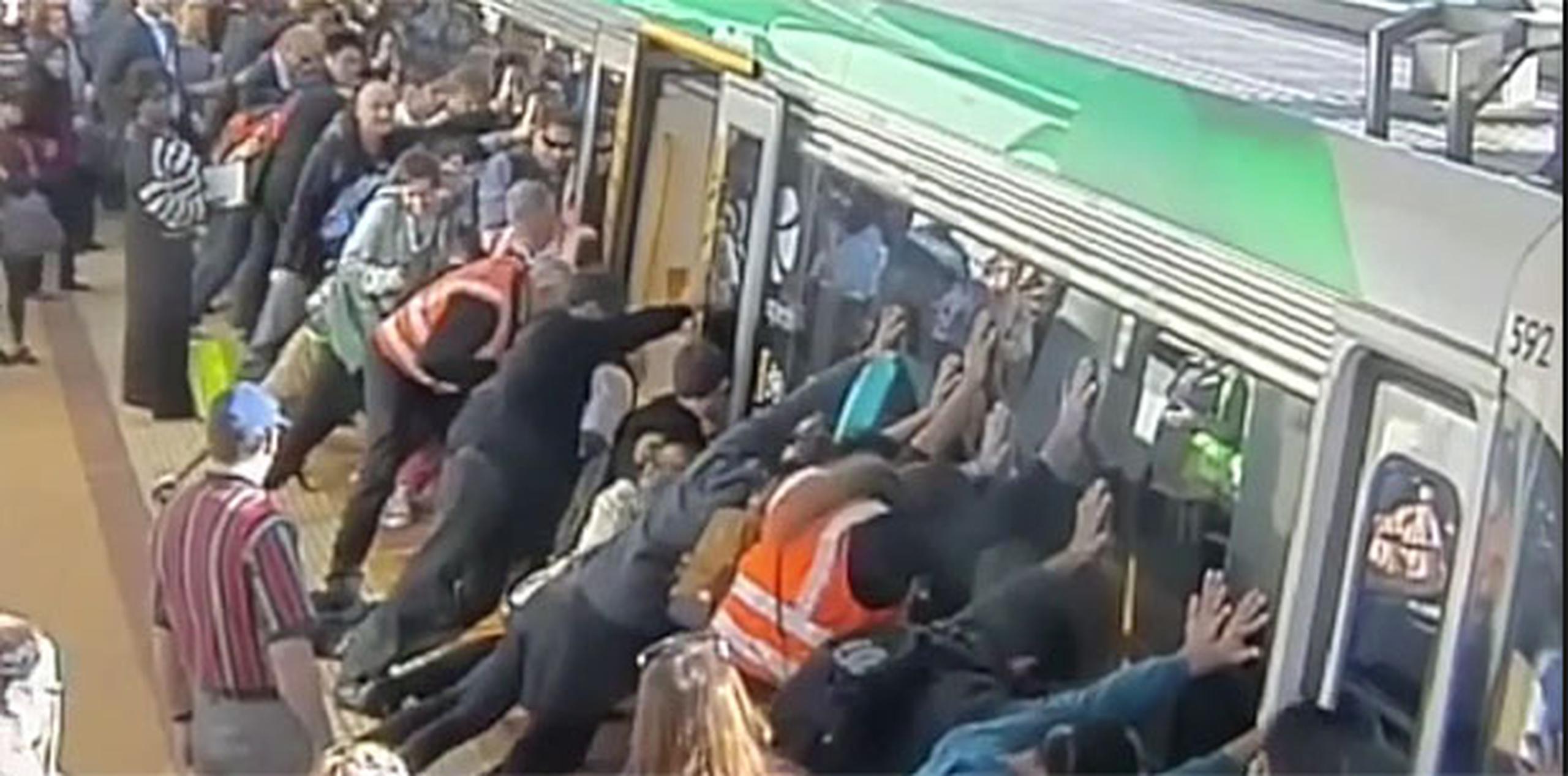 Las imágenes muestran a decenas de personas que acuden a empujar el vagón para ladearlo y liberar al hombre, que había caído hasta la altura del muslo en el hueco. (YT)