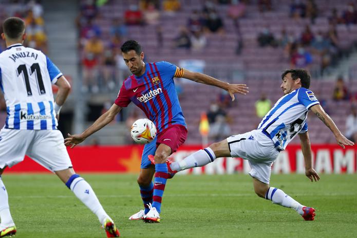 David Silva (derecha) de la Real Sociedad pugna un balón con Sergio Busquets del Barcelona en un partido de la Liga española, el domingo 15 de agosto de 2021. (AP Foto/Joan Monfort)