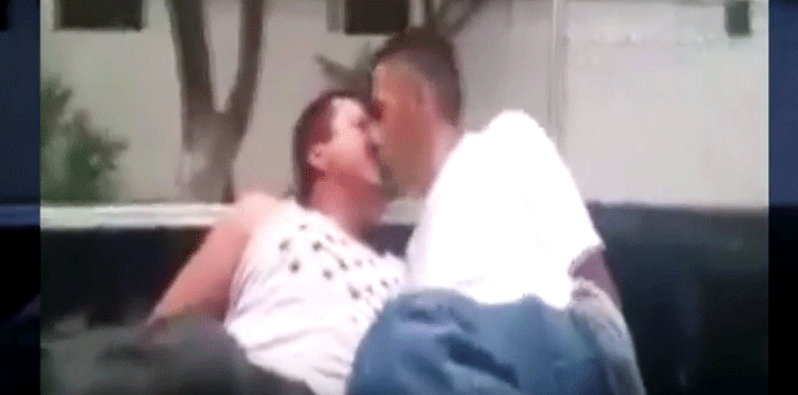 En la imagen se aprecia a dos hombres esposados en la parte trasera de una patrulla tipo pick up, y un hombre les plantea que se den un beso para ser puestos en libertad. (YouTube)