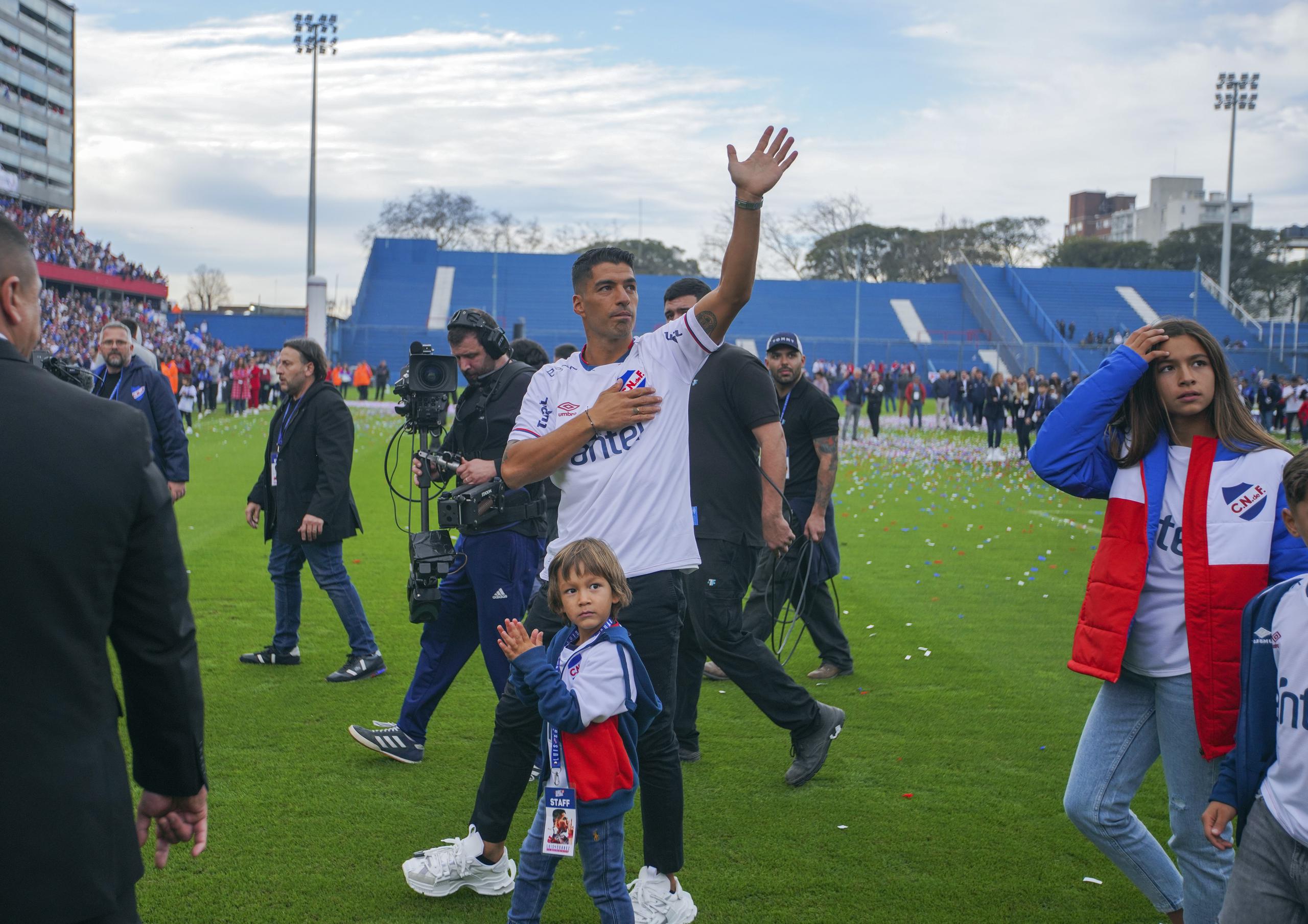 Acompañado por su familia, el astro uruguayo Luis Suárez saluda al público tras llegar al Gran Parque Central, el estadio de Nacional de Montevideo, el domingo 31 de julio de 2022. (AP Foto/Matilde Campodónico)