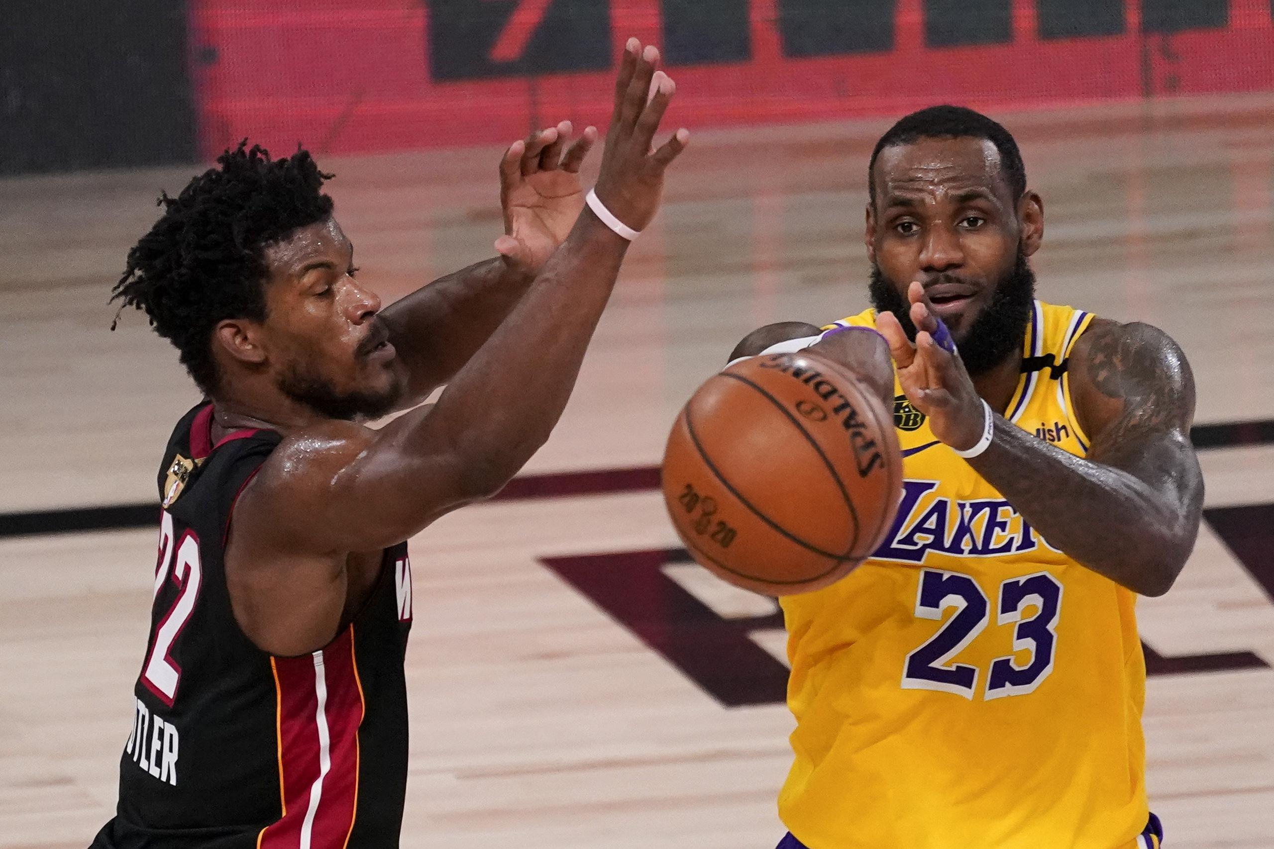LeBron James, de los Lakers, pase el balón contra Jimmy Butler, del Heat, en el cuarto juego de las Finales de la NBA.