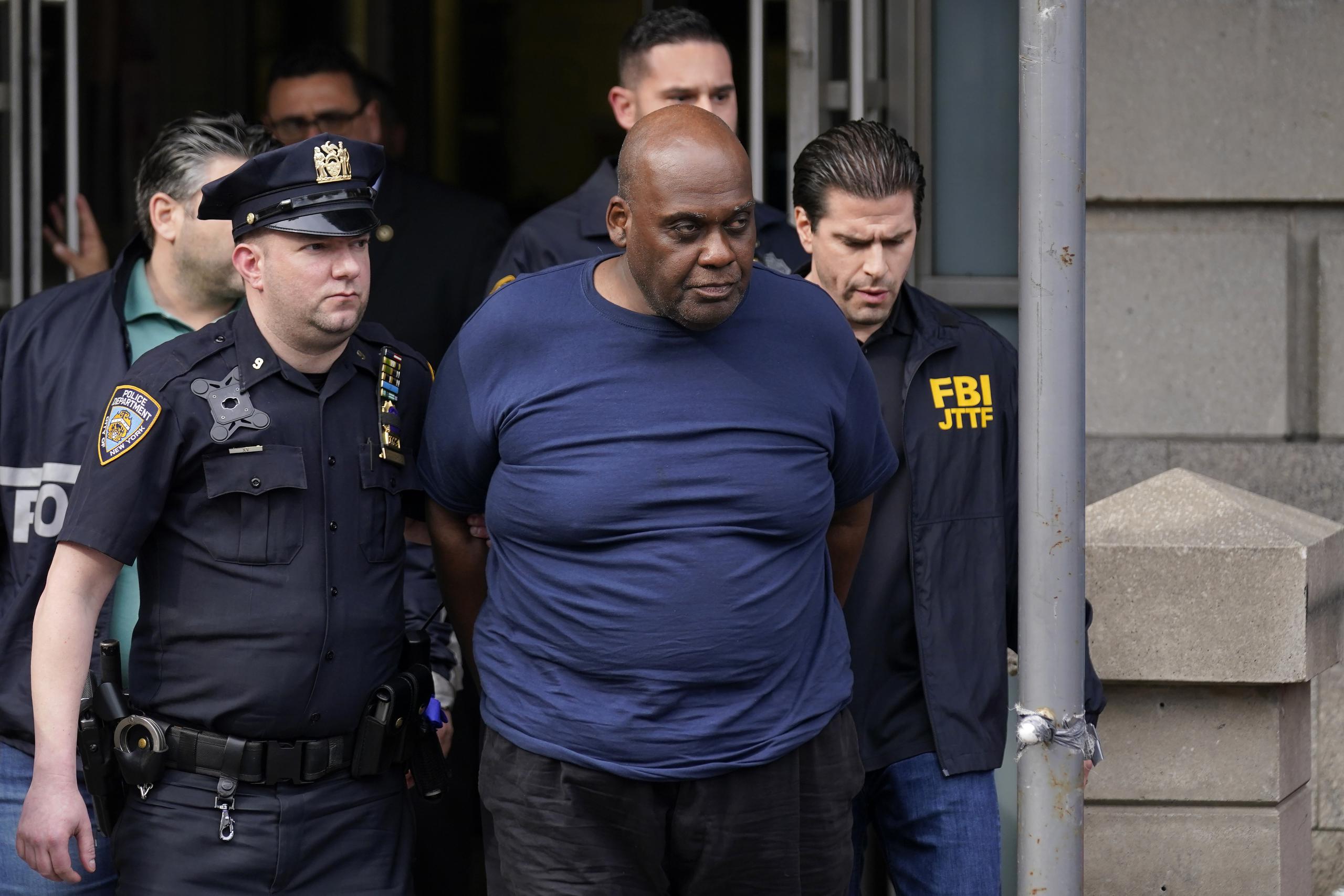 Policías salen de una comisaría con Frank James, de 62 años, autor de un tiroteo en el metro en Nueva York.