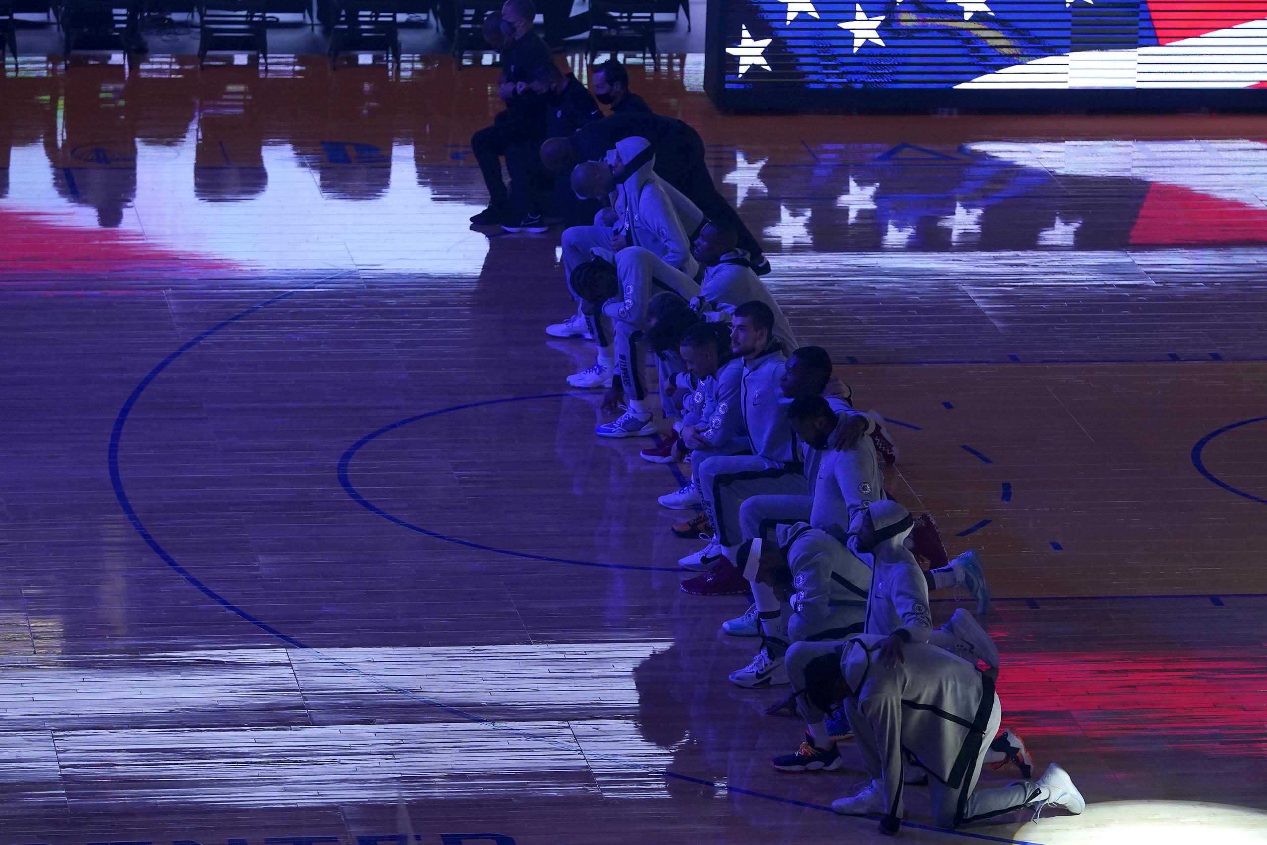 Los jugadores y entrenadores de los Clippers de Los Ángeles se arrodillan durante el himno nacional antes de un partido de baloncesto de la NBA contra los Warriors de Golden State en San Francisco.