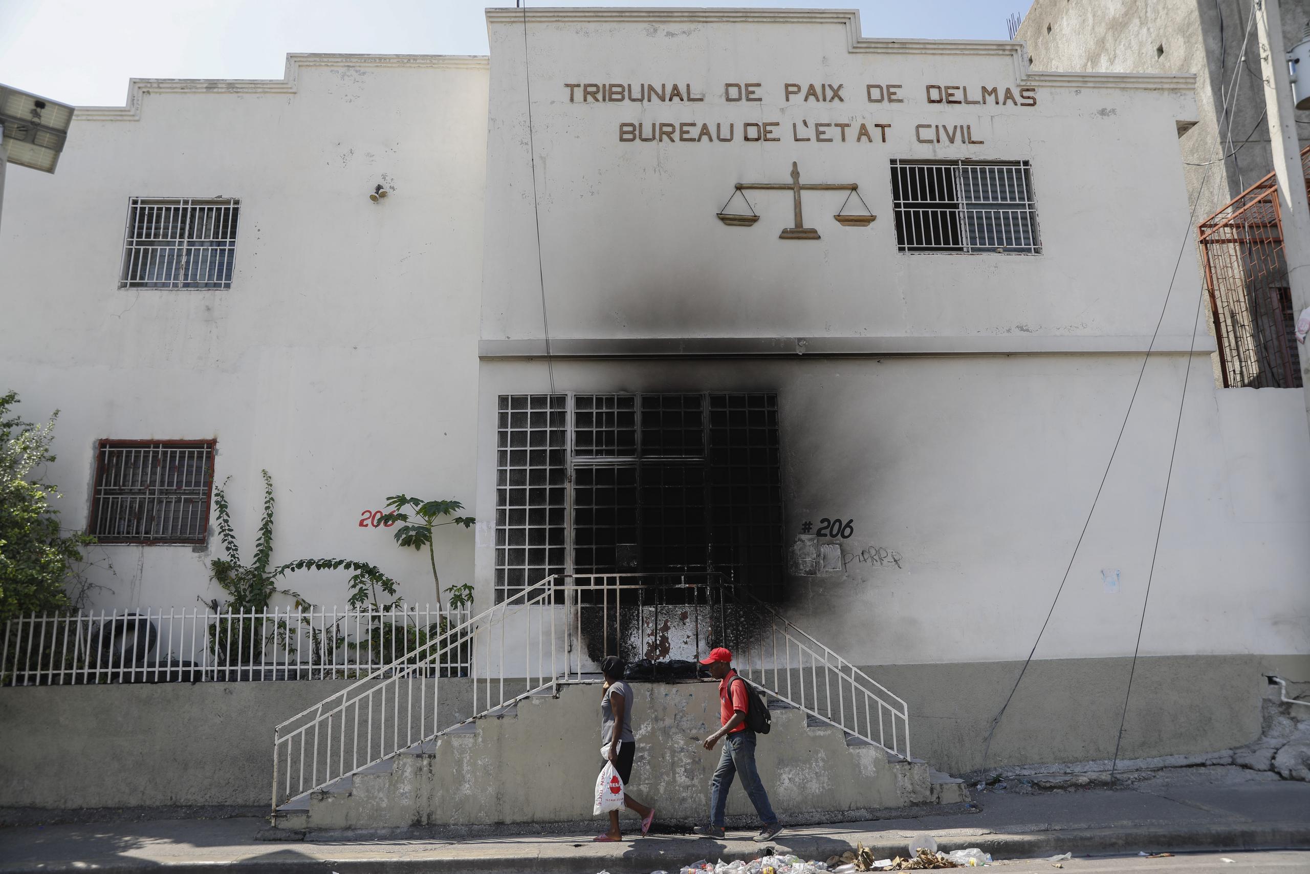 Dos peatones pasan junto a un edificio judicial que fue incendiado por pandillas en el barrio Delmas 28 de Puerto Príncipe, Haití, el 6 de marzo de 2024. (Foto AP/Odelyn Joseph)