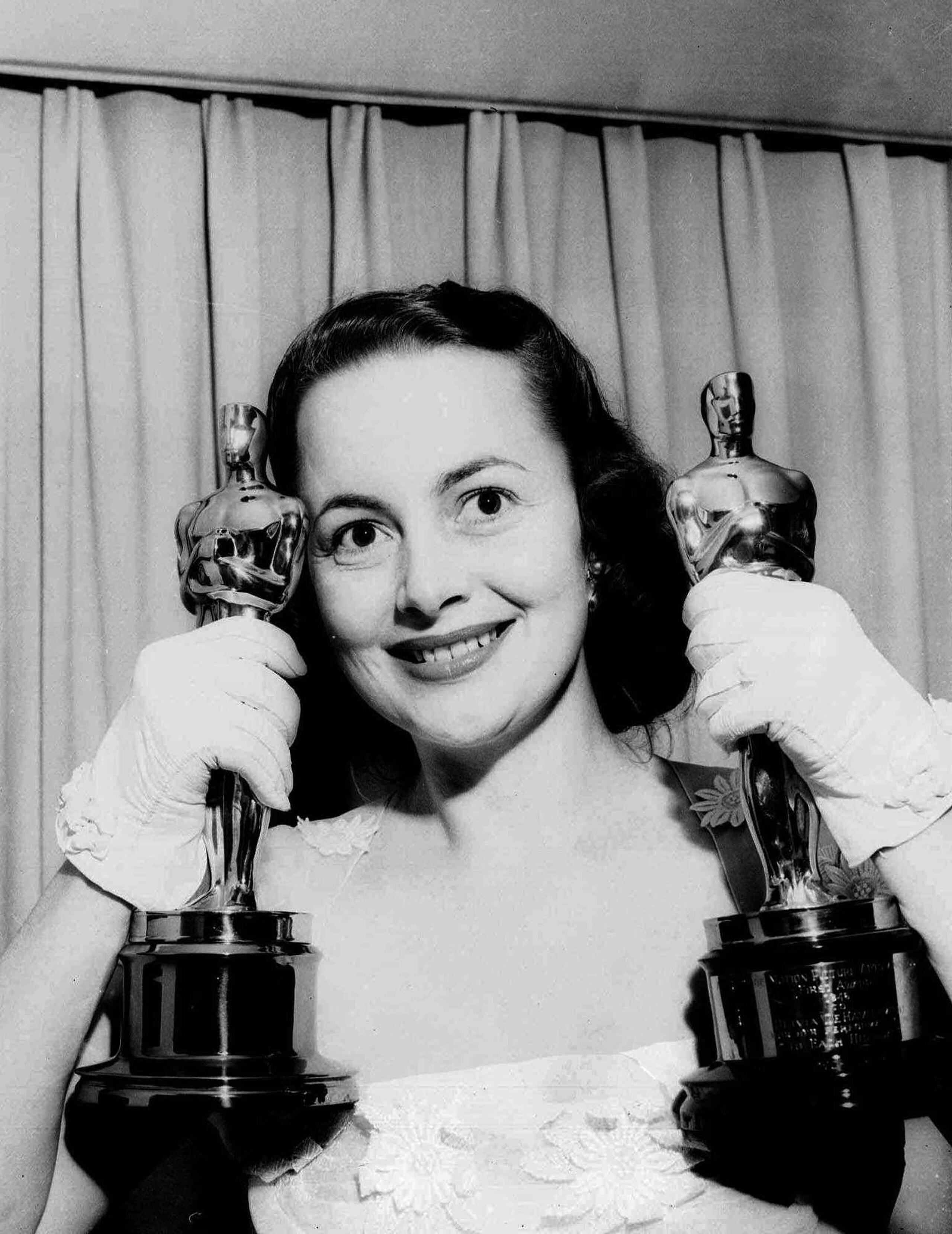 Olivia de Havilland, en una foto tomada en su hogar en 1950 sosteniendo sus dos premios de la Academia de Artes y Ciencias Cinematográficas. Ese año ganó el Oscar por su actuación en "The Heiress."  En 1946 había recibido su primera estatuilla por "To Each His Own."