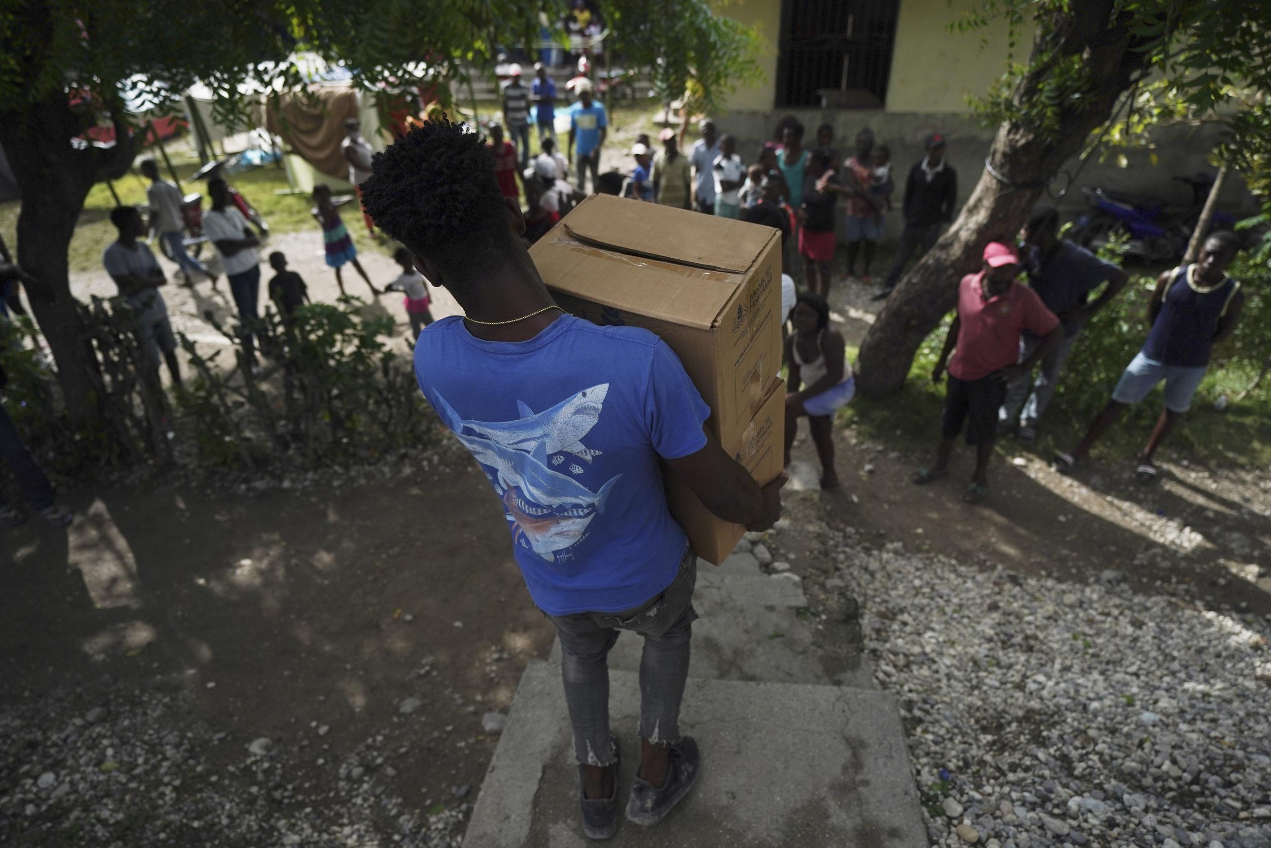 Un hombre carga dos cajas que contienen alimentos, en Les Cayes, Haití, las cuales fueron enviadas por el gobierno de la ciudad para los residentes que se quedaron sin hogar luego del sismo de magnitud de 7.2 que sacudió la nación.