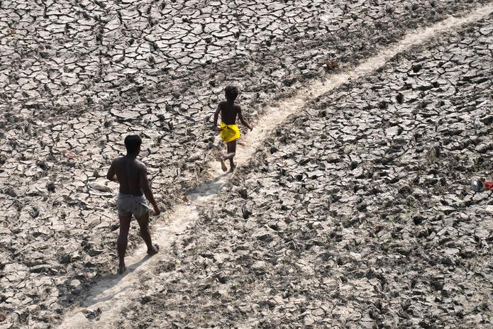 Un hombre y un niño caminan a través del lecho casi seco del río Yamuna luego de una ola de calor, el 2 de mayo de 2022, en Nueva Delhi.