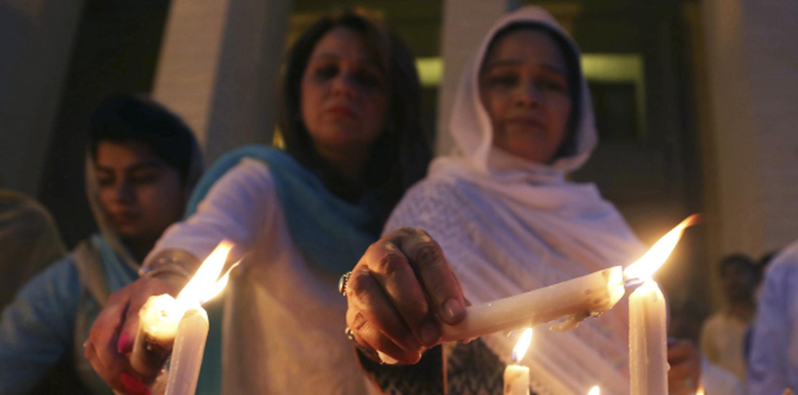 Varios miembros de la asamblea provincial de Sindh, Pakistán, encienden velas durante una vigilia por las víctimas del tiroteo reciente contra un autobús protagonizado por EI. (EFE)