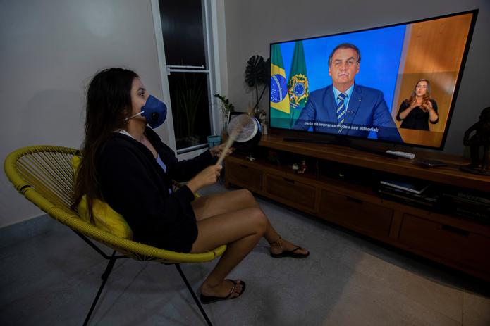 Una mujer con una máscarilla protesta golpeando una olla durante una declaración televisda del presidente de Brasil, Jair Bolsonaro