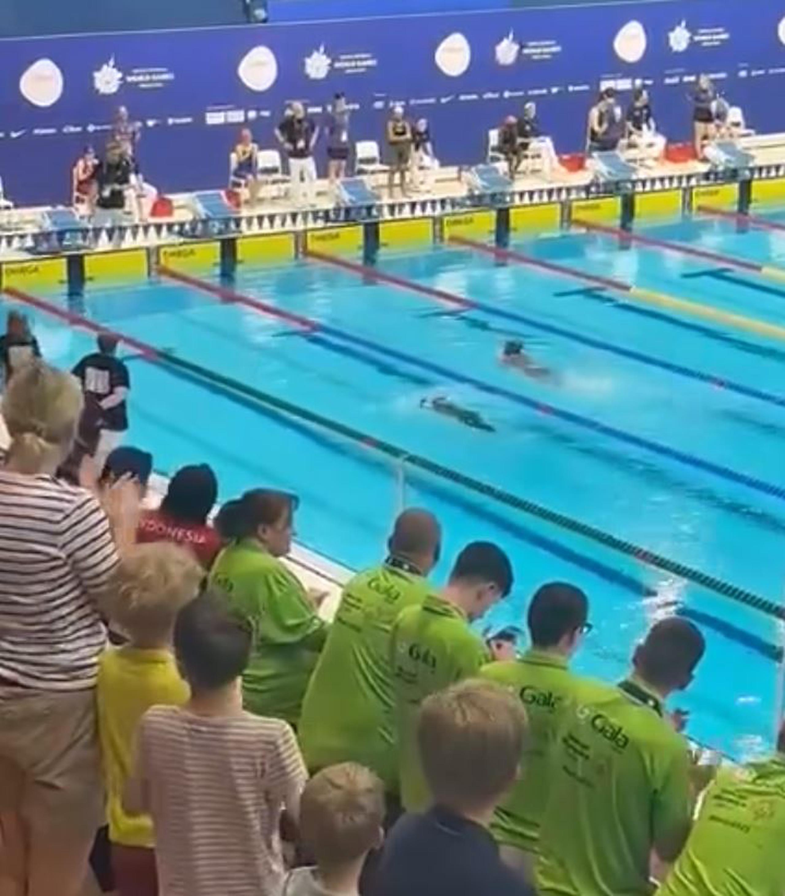 Esmeralda Despiau, la nadadora en el carril derecho, ayuda a una joven de Arabia Saudí a terminar su prueba en las eliminatorias de los 100 metros.