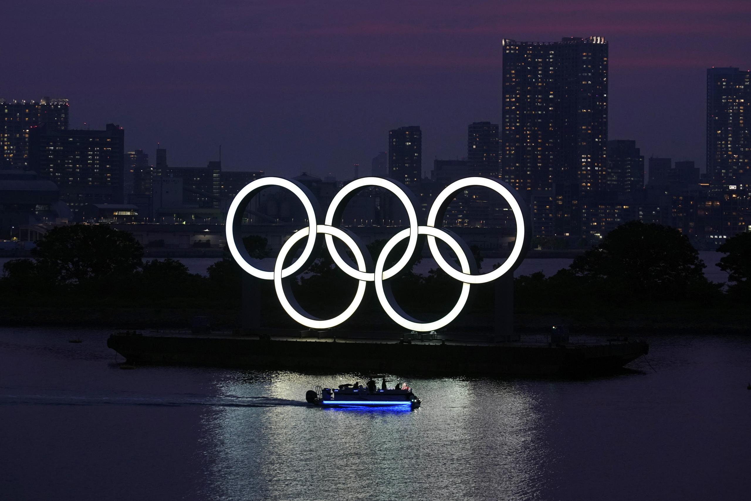 En esta foto, los anillos olímpicos flotan sobre el agua al atardecer en Tokio.