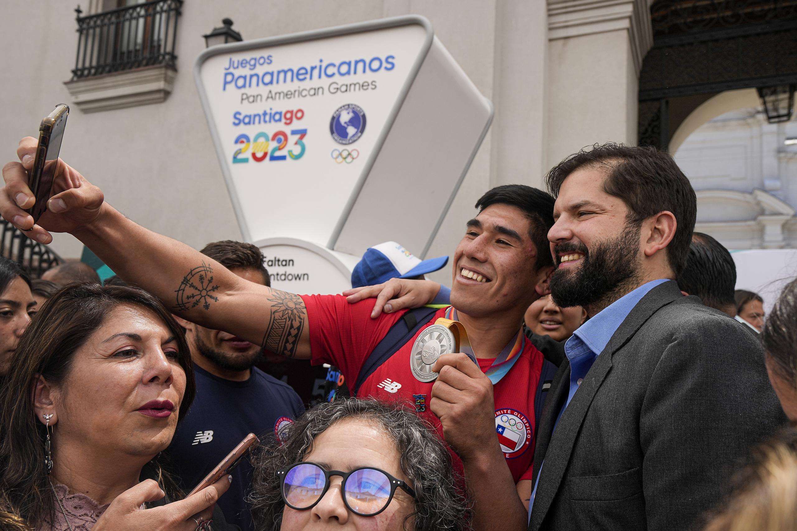 El presidente chileno Gabriel Boric posa para una selfie con un deportista chileno durante la ceremonia que marcó el inicio de la cuenta regresiva para los Juegos Panamericanos y Parapanamericanos de 2023.