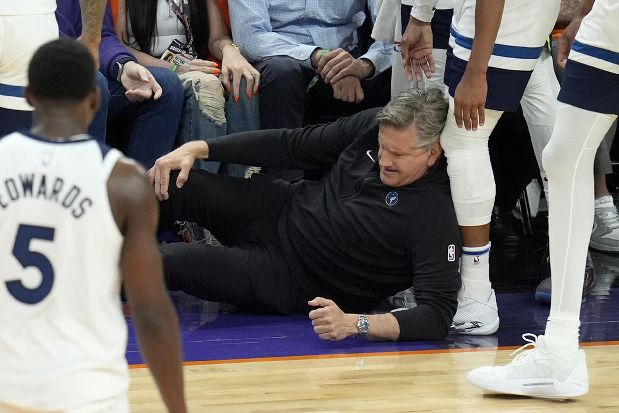 El dirigente de los Timberwolves de Minnesota, Chris Finch, se sujeta de la rodilla tras chocar con  Mike Conley durante el cuarto partido contra los Suns de Phoenix.